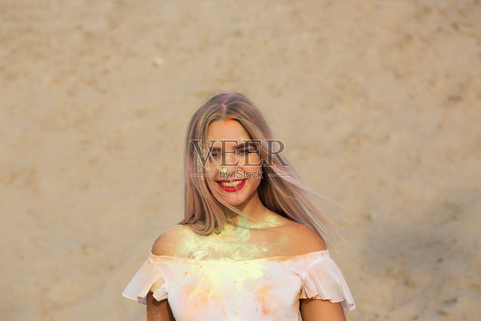 特写镜头:在沙漠里，兴奋的金发女人身上涂满了绿色的干漆照片摄影图片