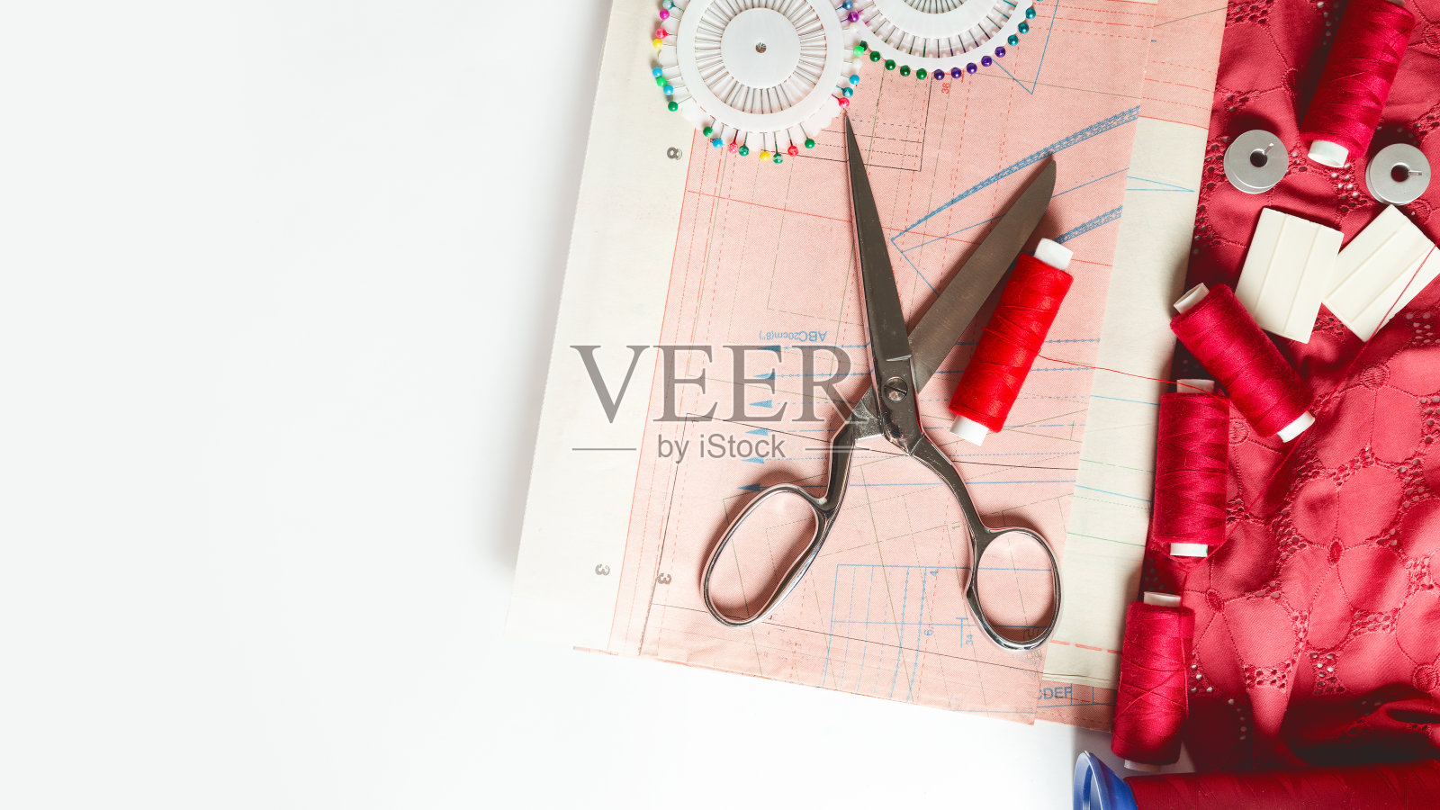 时尚背景。图案，织物，别针，线和各种设计师的配件在一个白色的桌子上，俯视图。空间的文本照片摄影图片