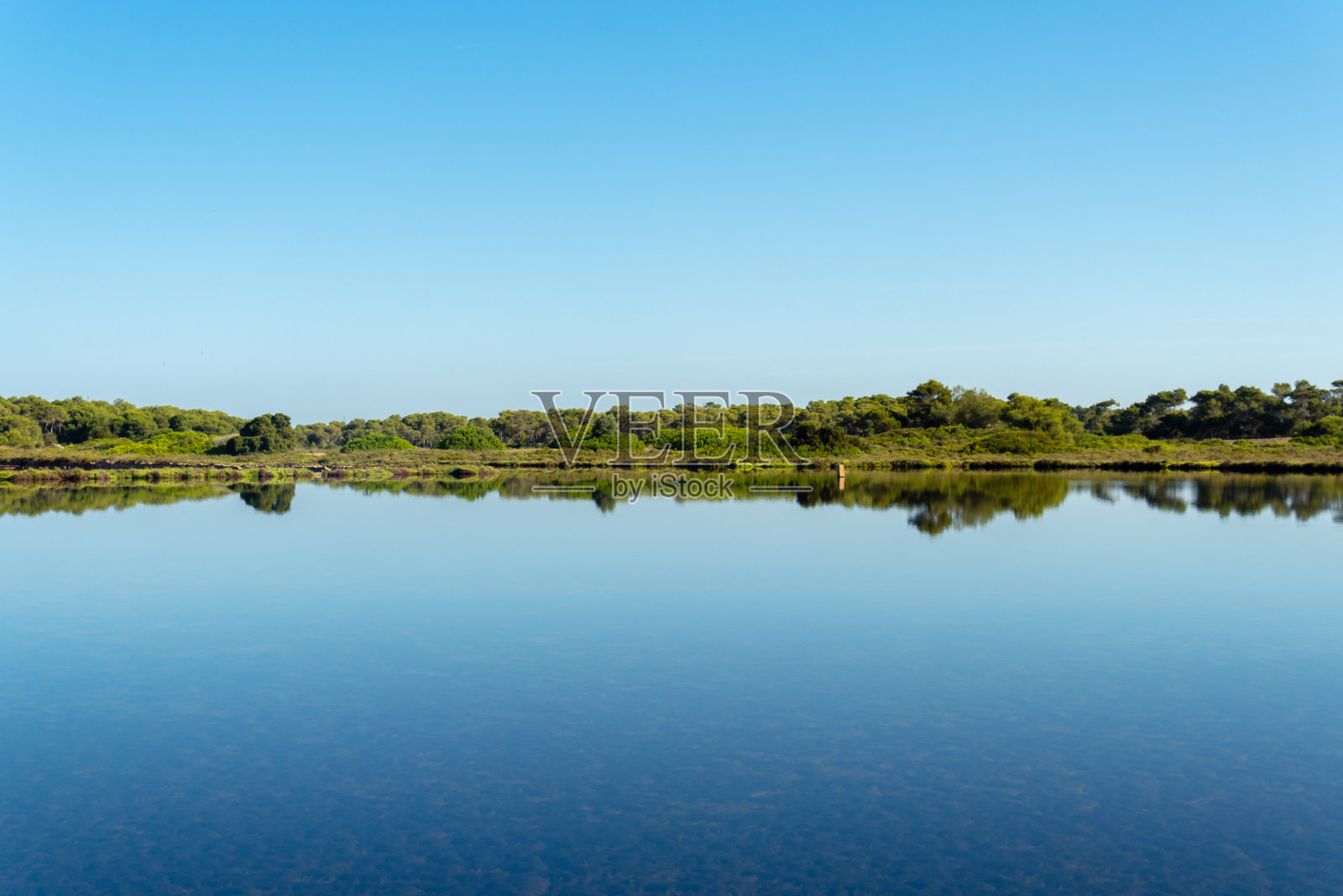 太阳升起时，映照在盐厂池塘中的马略卡岛圣乔尔迪城的全貌照片摄影图片