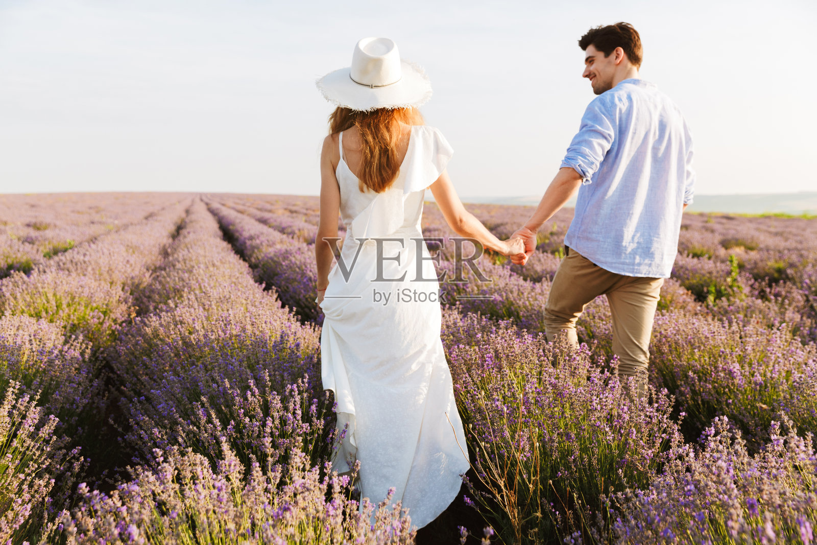 美丽的年轻夫妇的照片，男人和女人笑着，走在薰衣草田的户外照片摄影图片