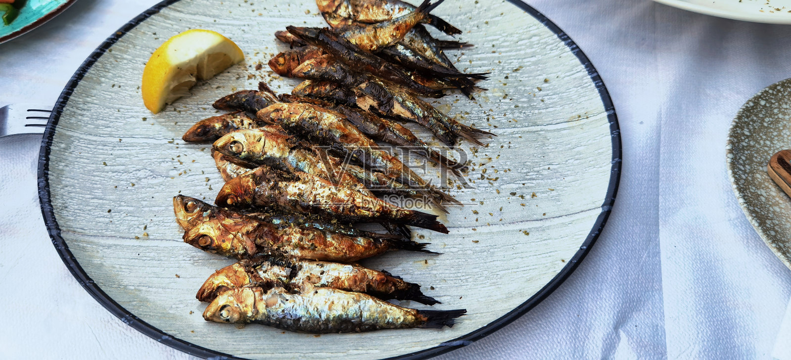 在希腊的Preveza，桌上的盘子里烤着沙丁鱼和鱼照片摄影图片
