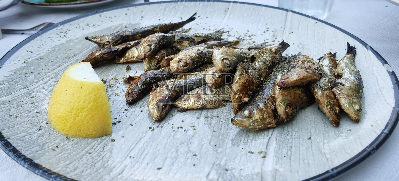 在希腊的Preveza，桌上的盘子里烤着沙丁鱼和鱼照片摄影图片
