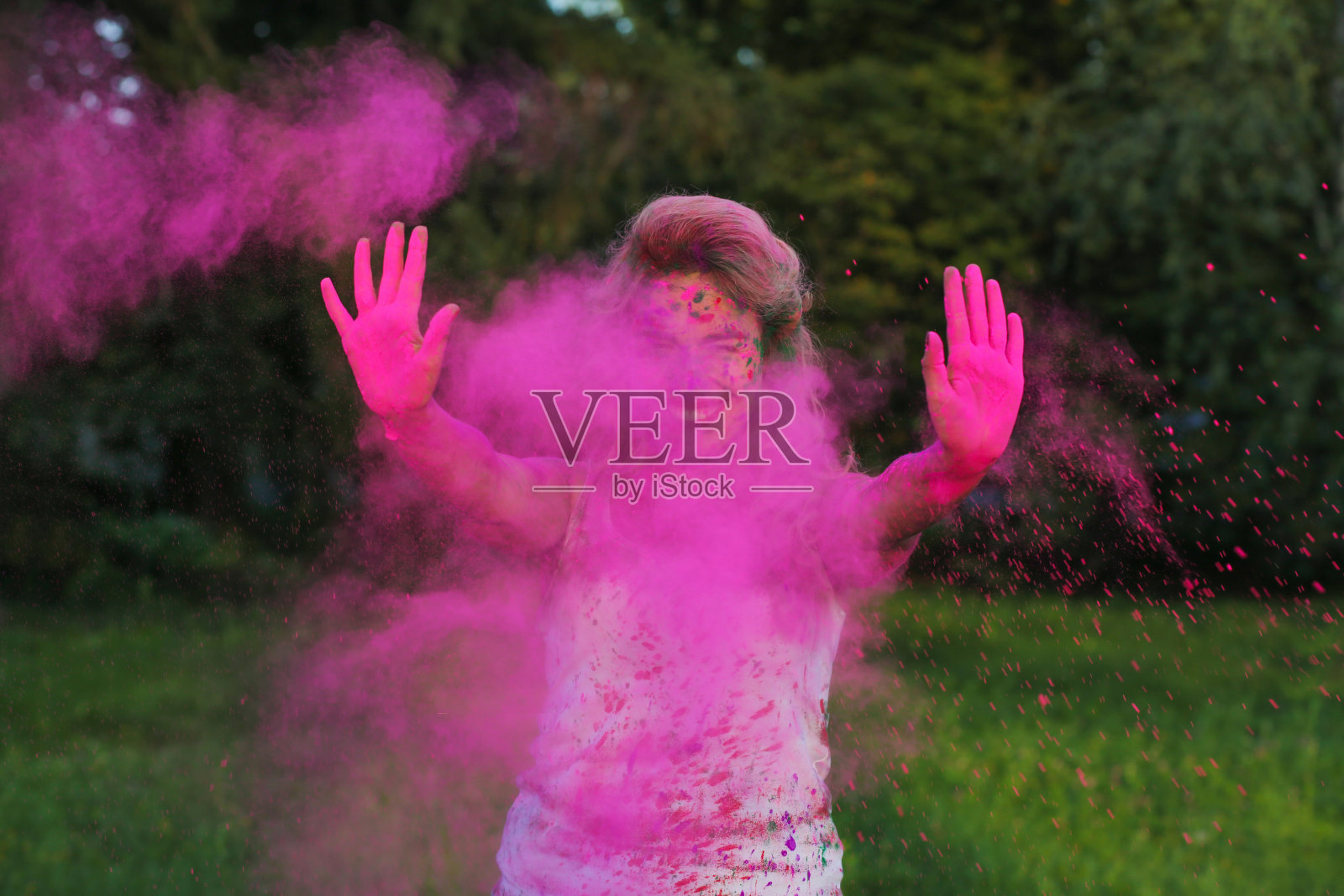 可爱的白人女孩与卷发摆姿势在一团粉红色的干油漆，庆祝胡里节照片摄影图片