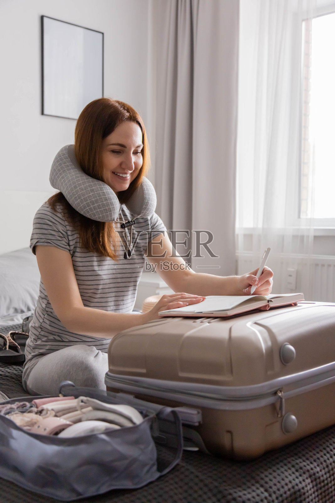 面带微笑的女游客打包行李去度假，写纸单子准备旅行旅行照片摄影图片