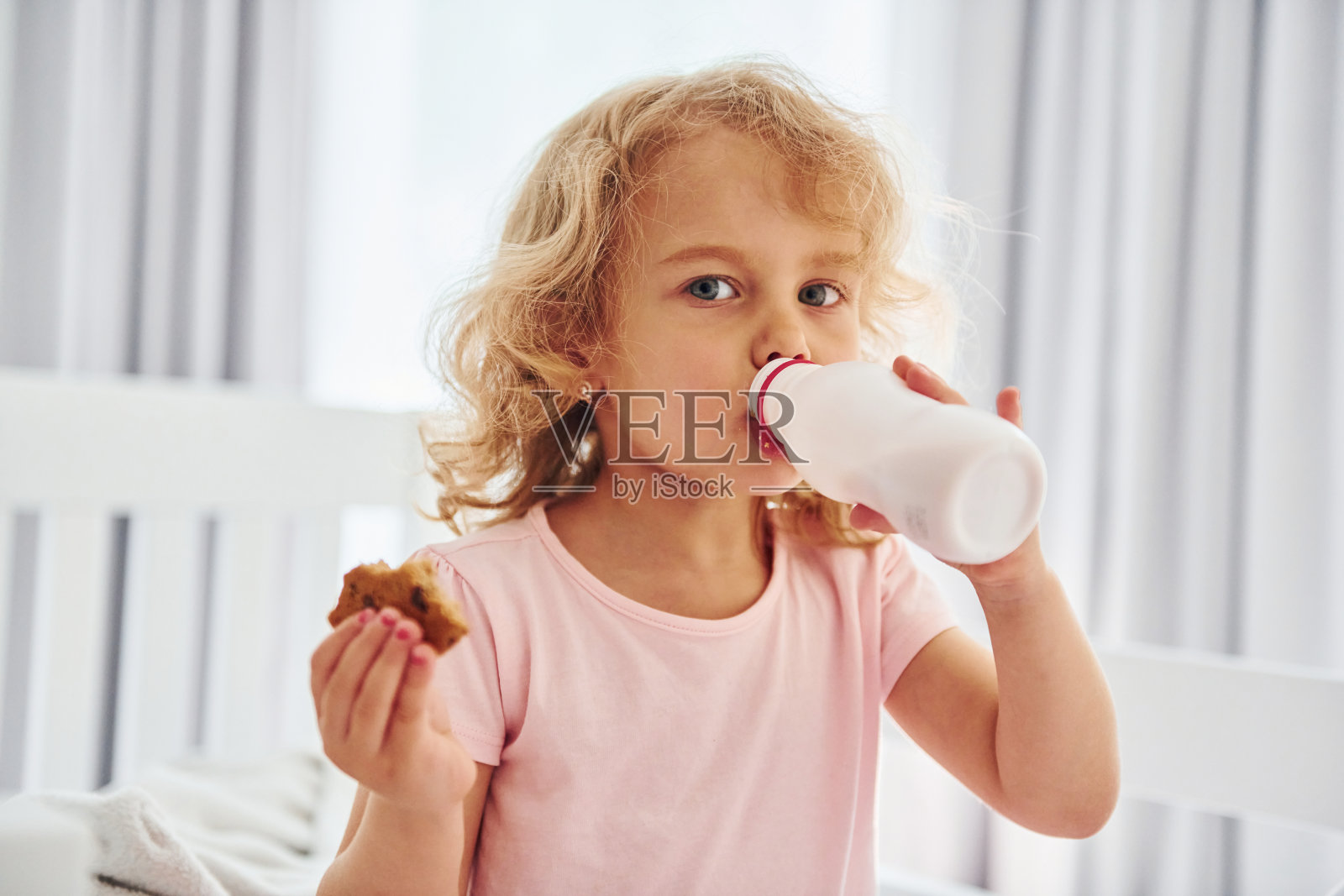 吃饼干吃早餐。可爱的小女孩白天穿着休闲的衣服待在家里照片摄影图片