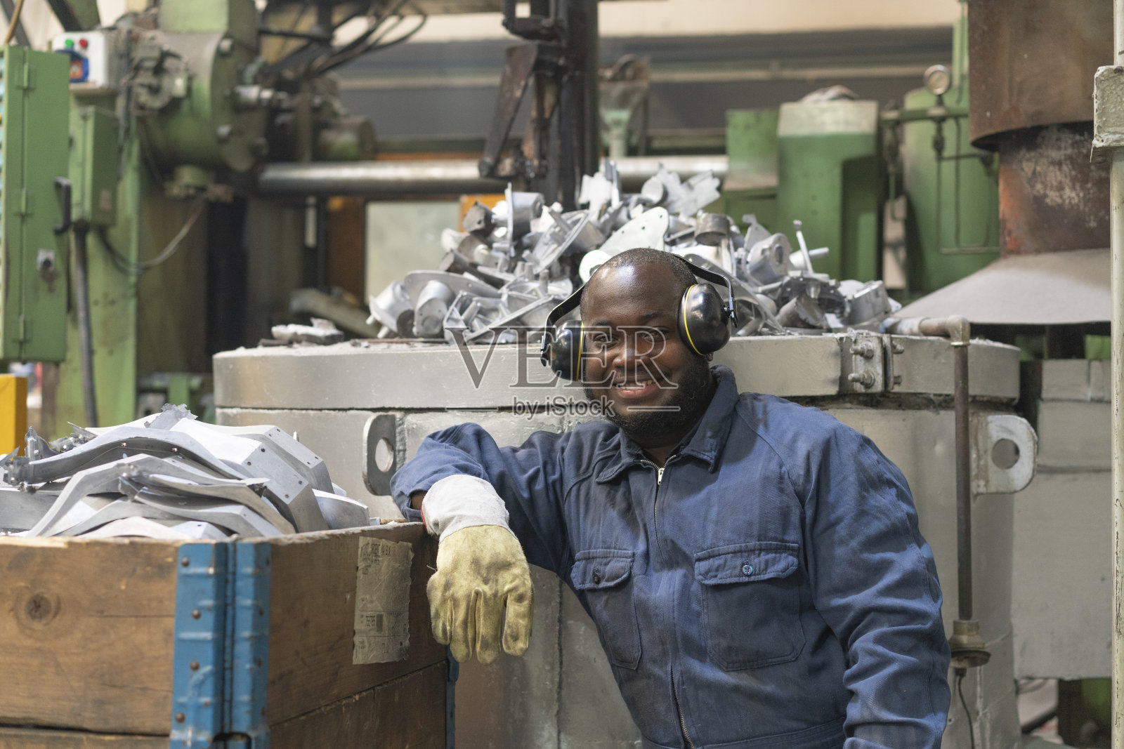一幅非裔美国工人在冶金厂金属零件附近快乐的肖像照片摄影图片