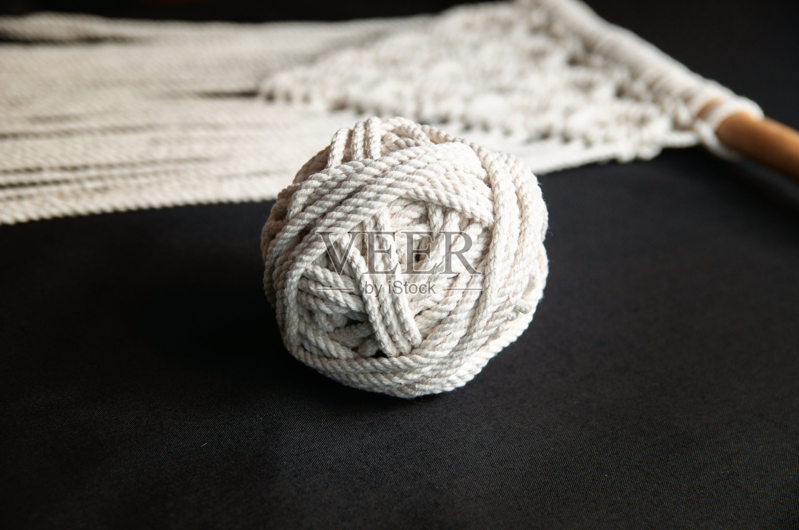 手工流苏100棉墙装饰用木棒挂在白色的墙上。室内的现代装饰。照片摄影图片