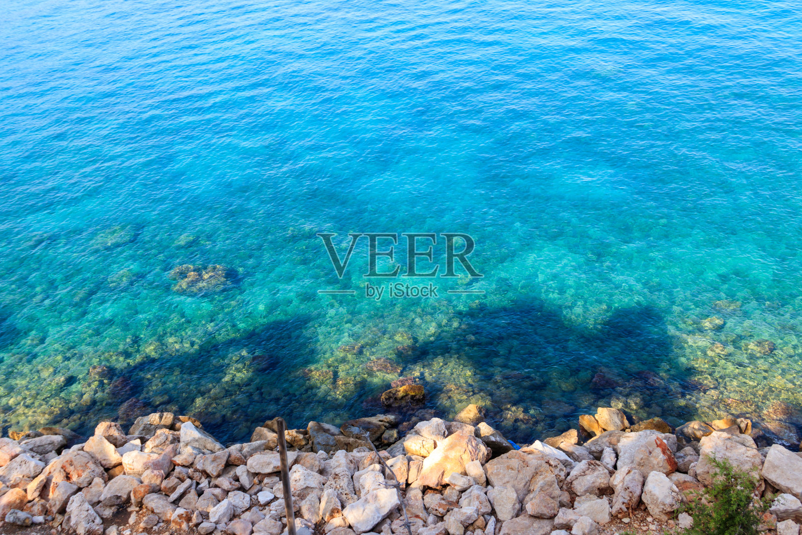 蓝色的水纹理背景。有多岩石海岸的地中海表面。俯视图照片摄影图片