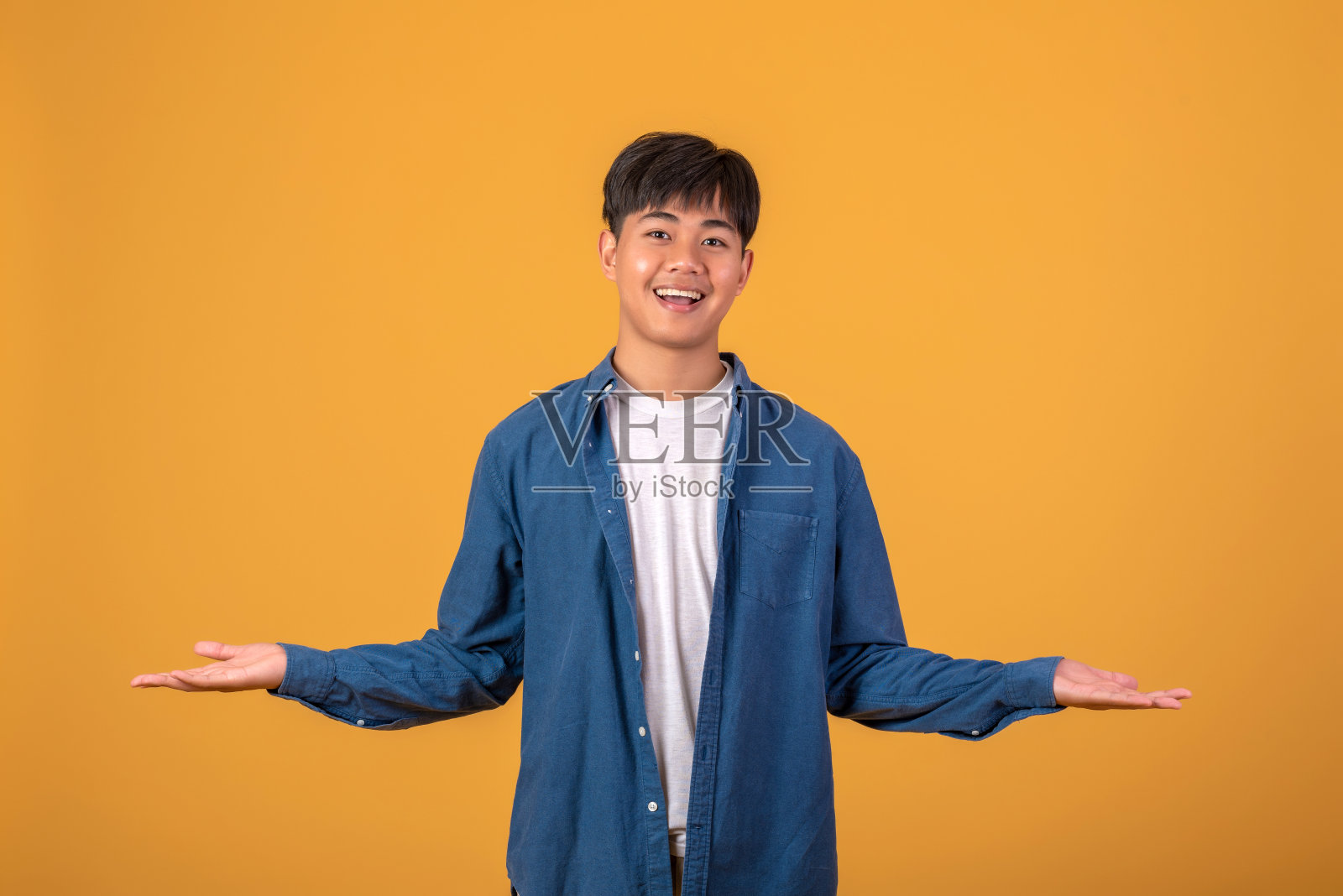 快乐微笑的年轻亚洲男子准备张开双臂时，接受友好积极的问候。橙色背景照片摄影图片