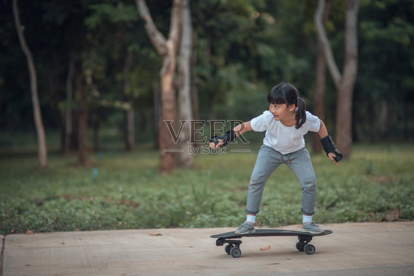 可爱的小女孩玩滑板或冲浪在滑板公园照片摄影图片