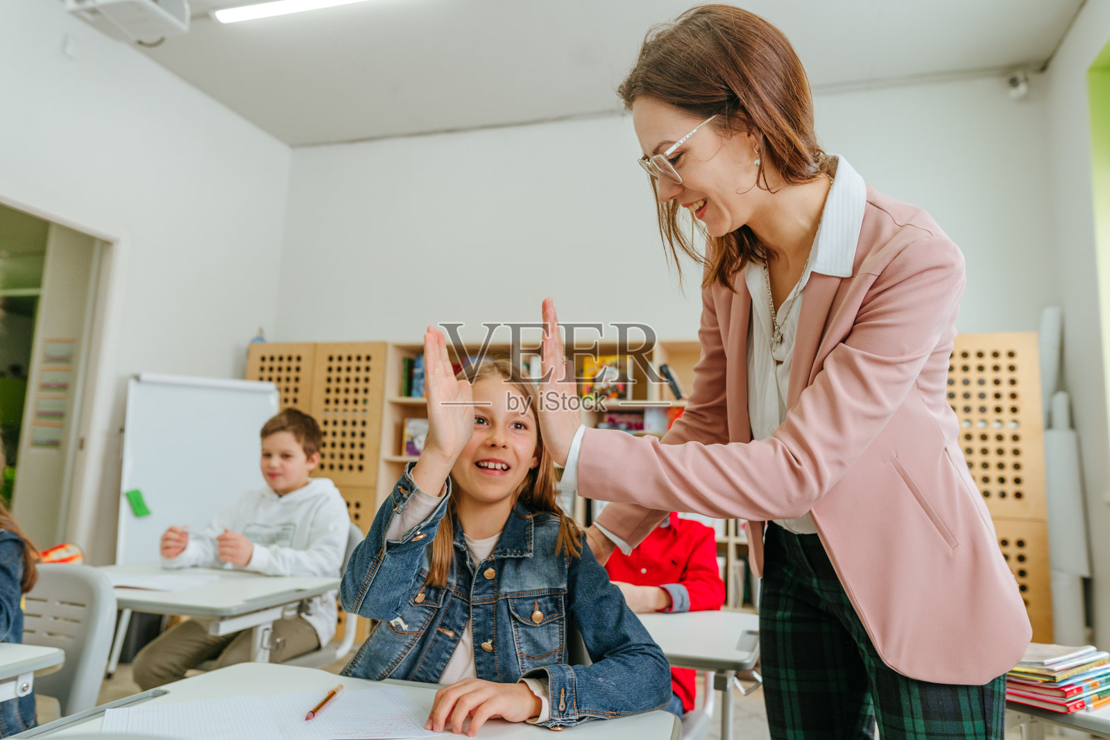 女老师帮助一个女学生指着她的笔记本上的东西照片摄影图片