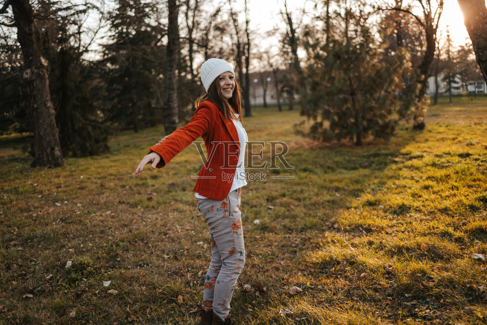 幸福美丽的年轻女子站在公园在秋天与伸出的手臂和微笑照片摄影图片