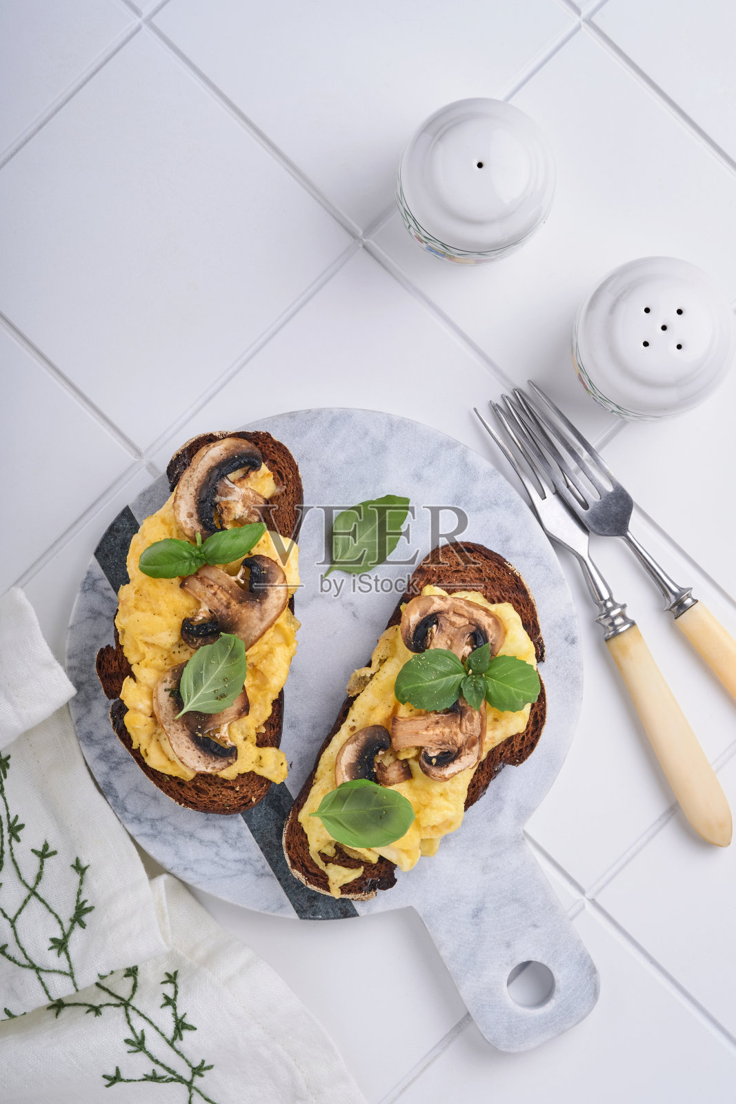 炒蛋，炸蘑菇和罗勒面包在白色的桌子背景。自制早餐或早午餐。炒鸡蛋和蘑菇三明治。顶部视图与复制空间照片摄影图片