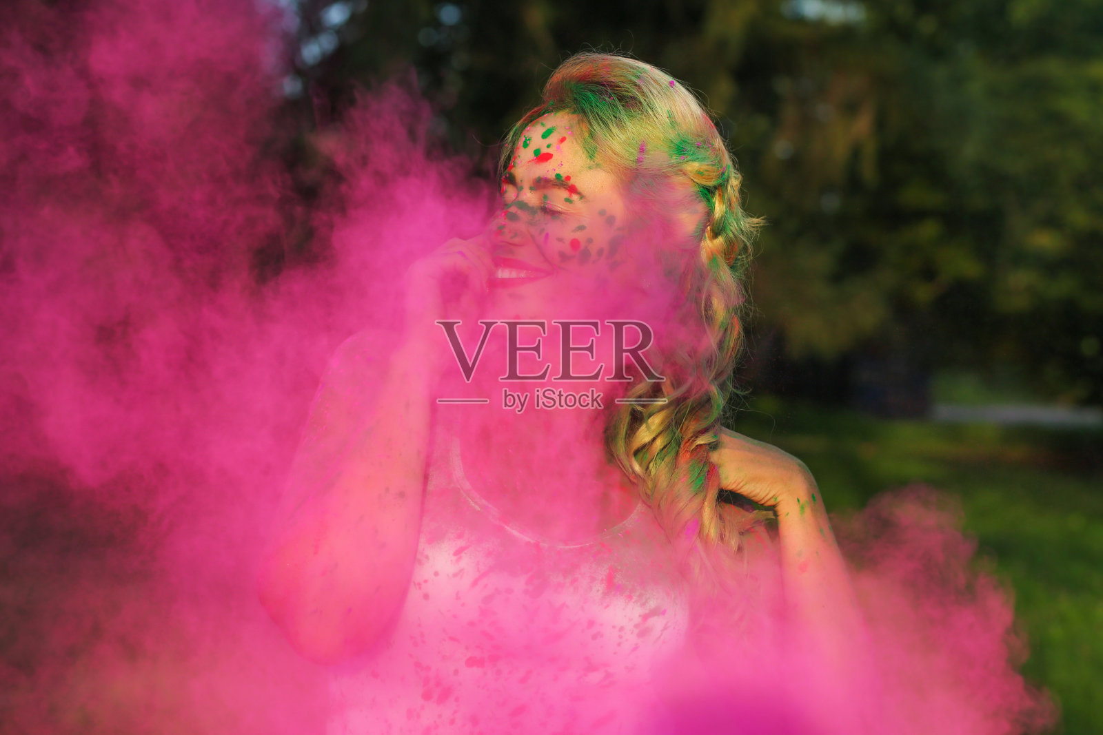 情绪化的高加索女孩与卷发站在粉红色的云干油漆，庆祝胡里节照片摄影图片