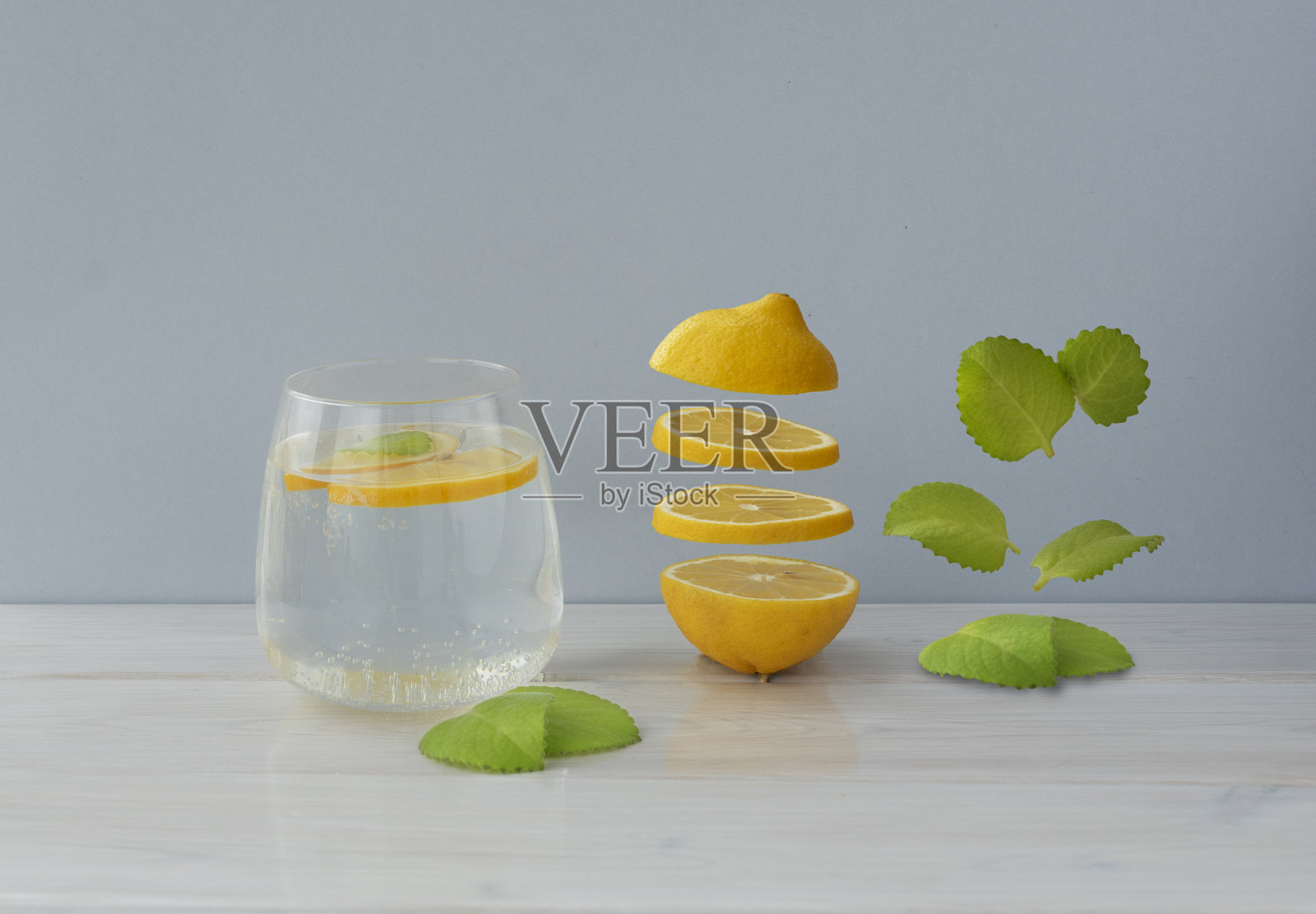 柠檬片和薄荷叶悬浮在一杯水附近的灯光背景，copyspace。照片摄影图片