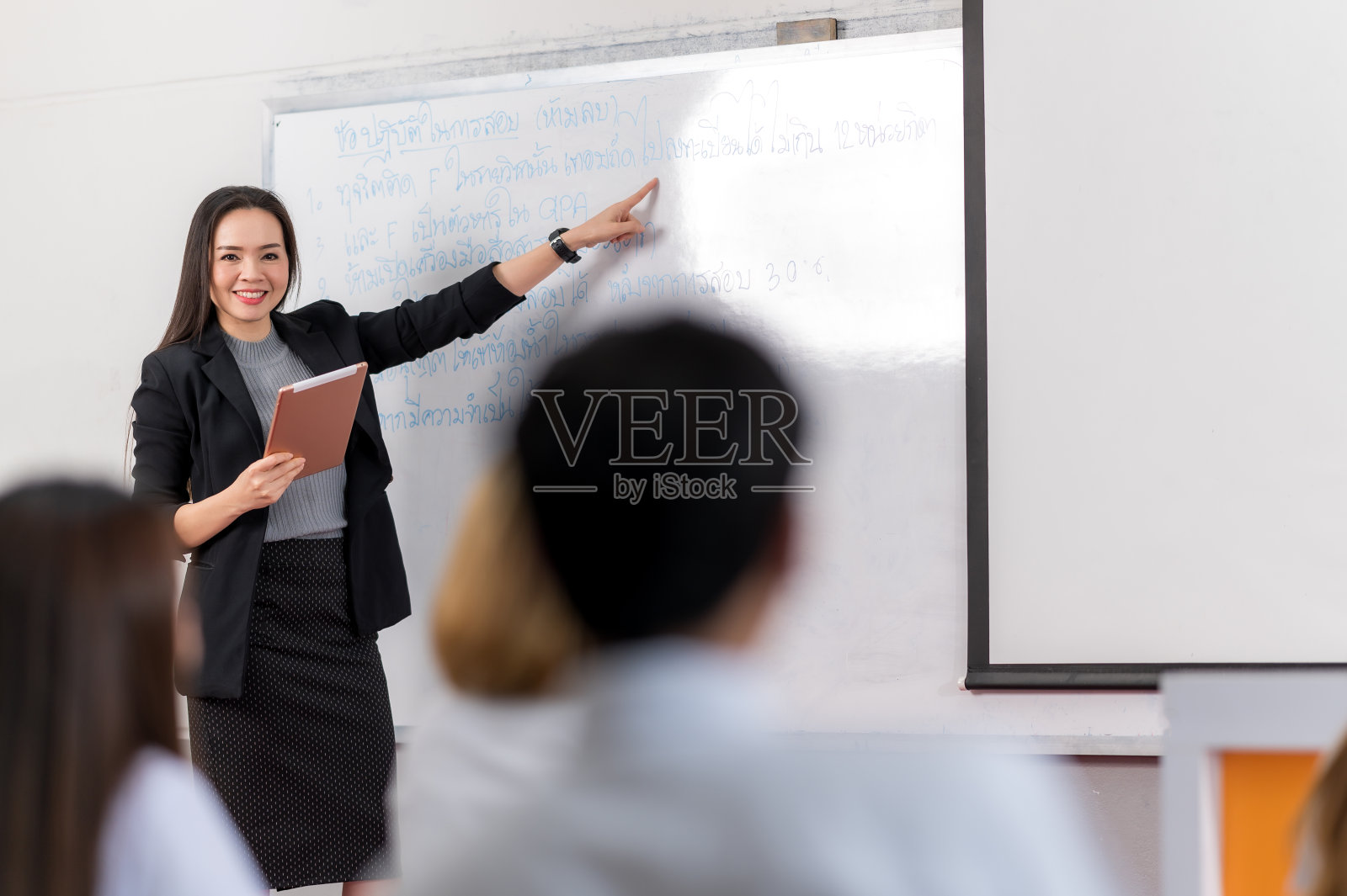 一位中年亚洲女教师在课堂上帮助一个学生在大学照片摄影图片