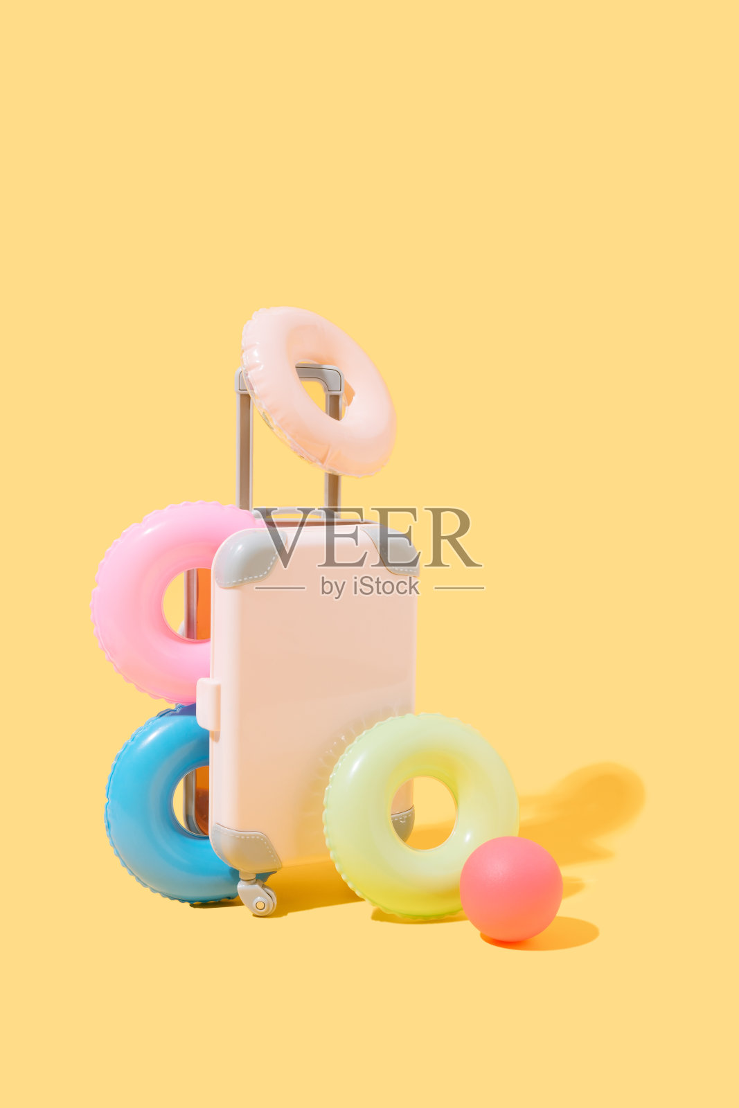 粉红色的手提箱，上面有许多花车和一个黄色背景上的球。旅行和夏天的概念。3 d演示。本空间照片摄影图片