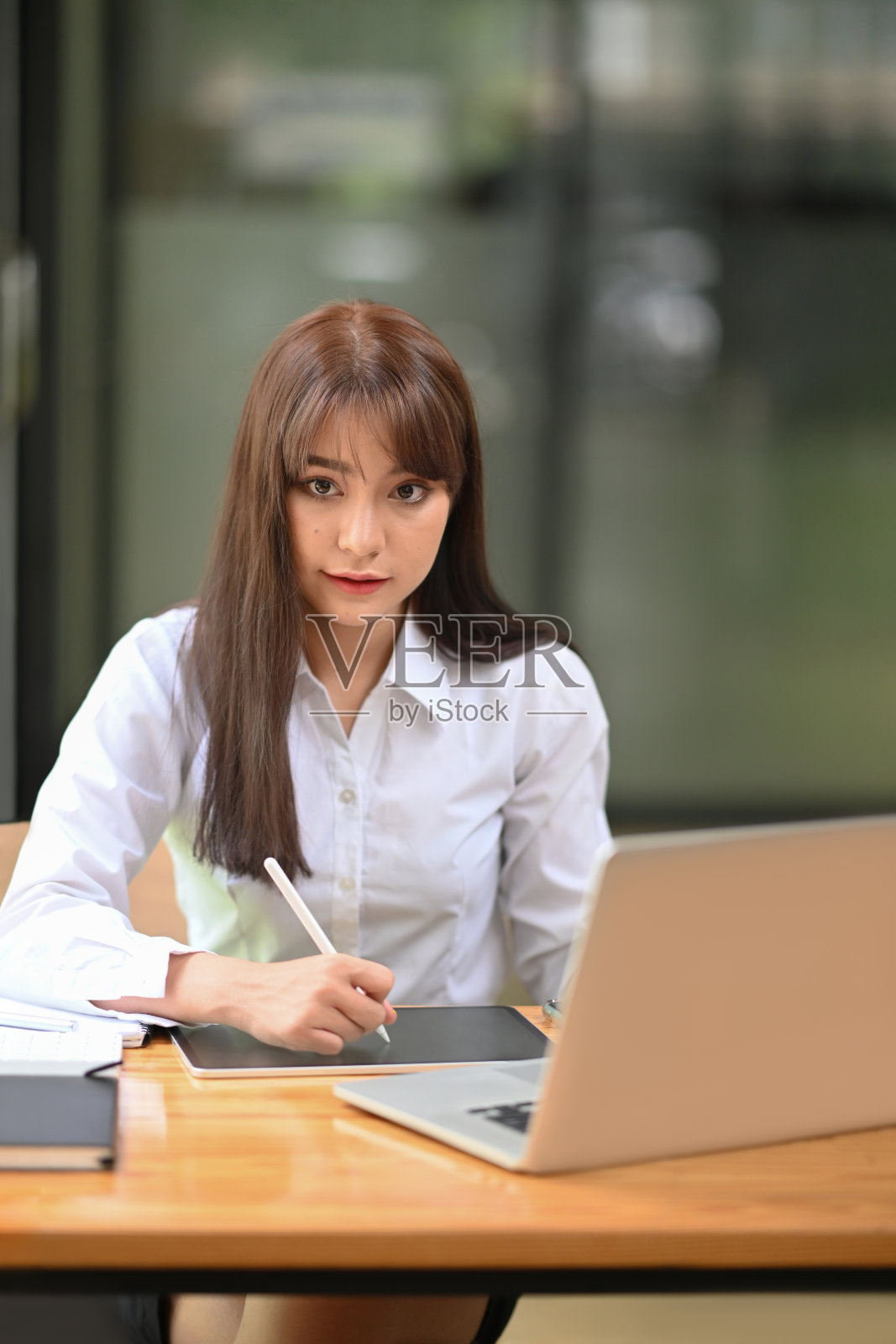 女性办公室工作人员与数字平板电脑和笔记本电脑的肖像。照片摄影图片