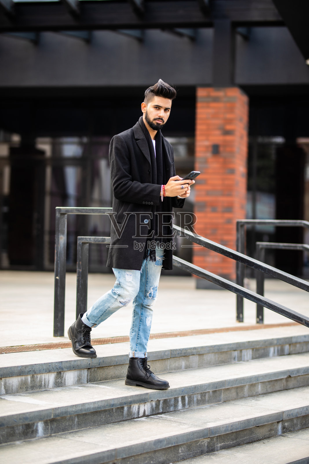 年轻英俊的商人站在楼梯上用手机照片摄影图片