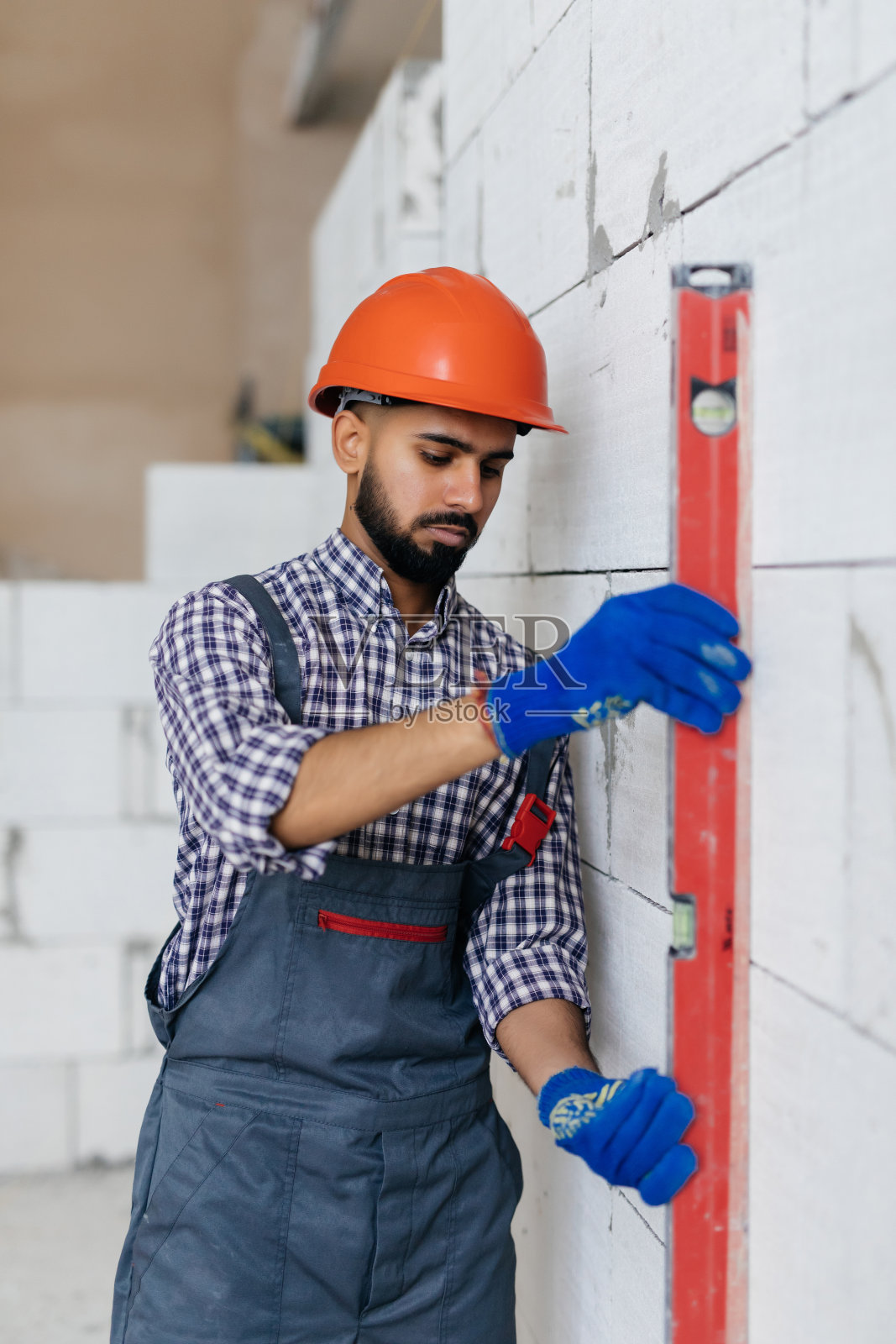 年轻的梅森正在检查由加气蒸压混凝土砌块制成的房屋墙壁的铅垂线照片摄影图片