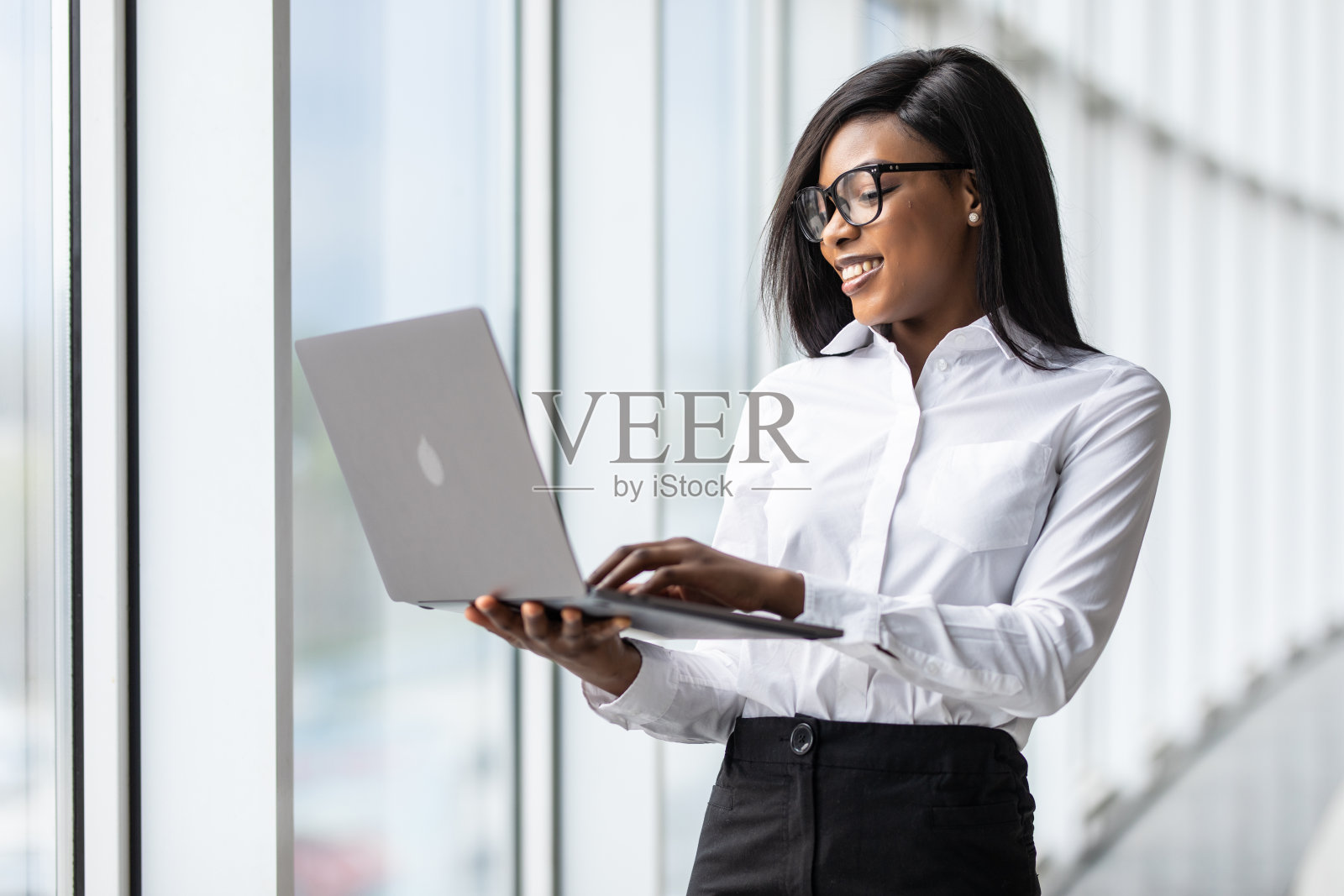 快乐年轻的非裔美国女商人在办公室使用笔记本电脑照片摄影图片