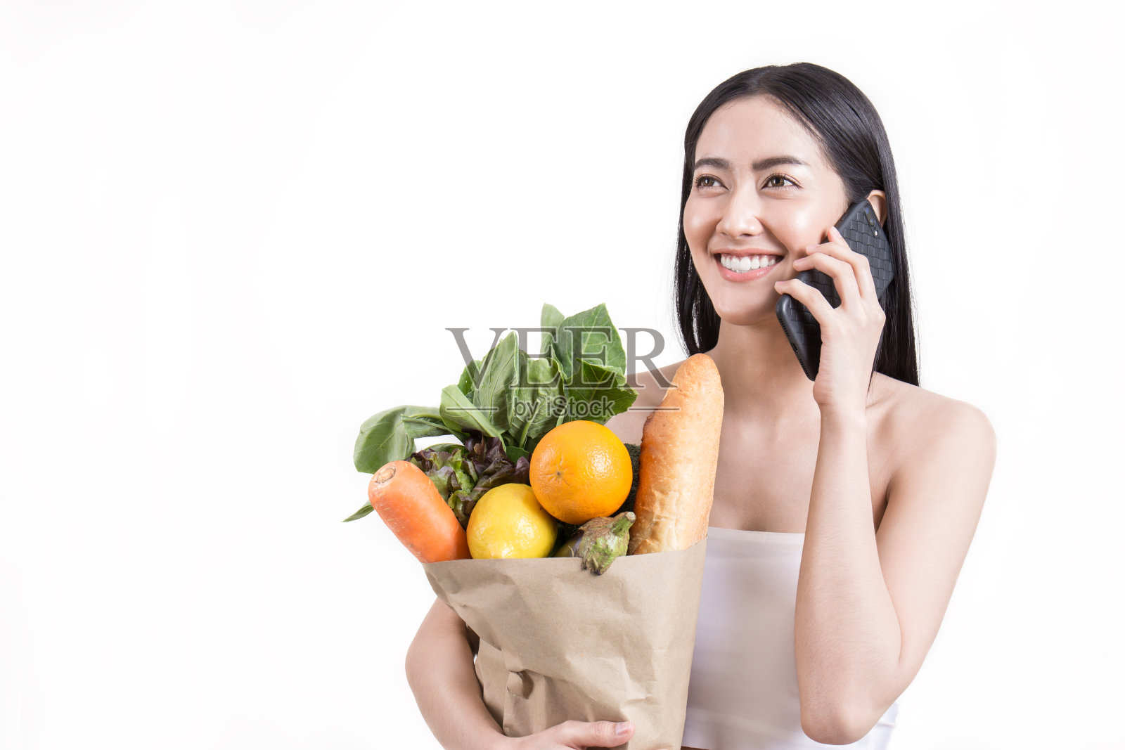特写美丽的亚洲女人拿着手机杂货蔬菜和食物孤立在白色的背景。健康生活方式网上购物电子商务电话营销配送理念。照片摄影图片