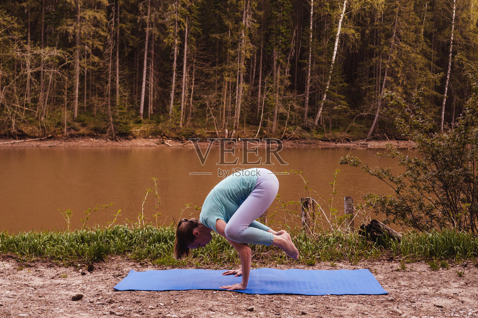年轻女子在河边做瑜伽，晚上。照片摄影图片
