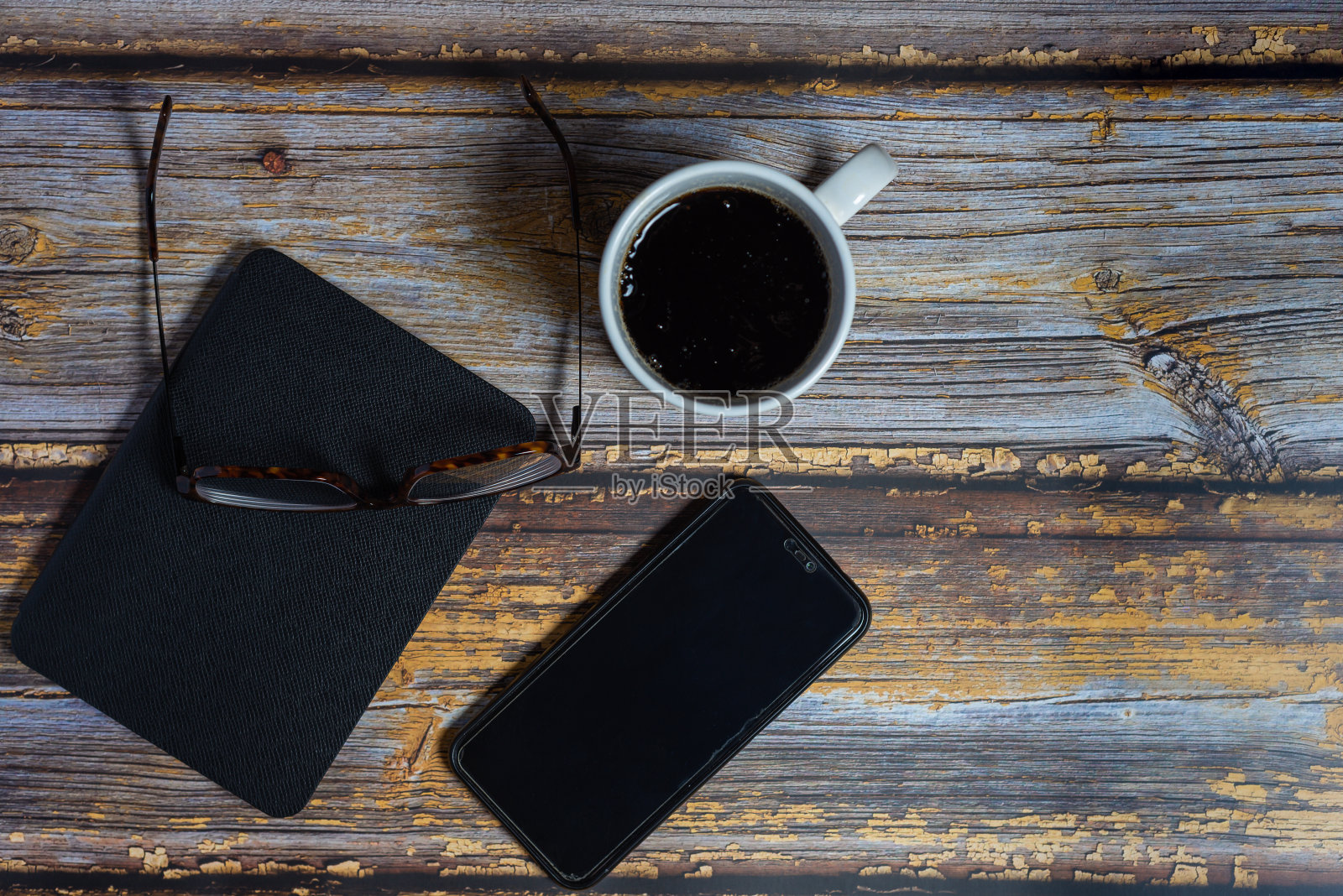 俯视图智能手机，电子书，平板电脑和眼镜，阅读与黑色屏幕为您的设计在古董木桌照片摄影图片