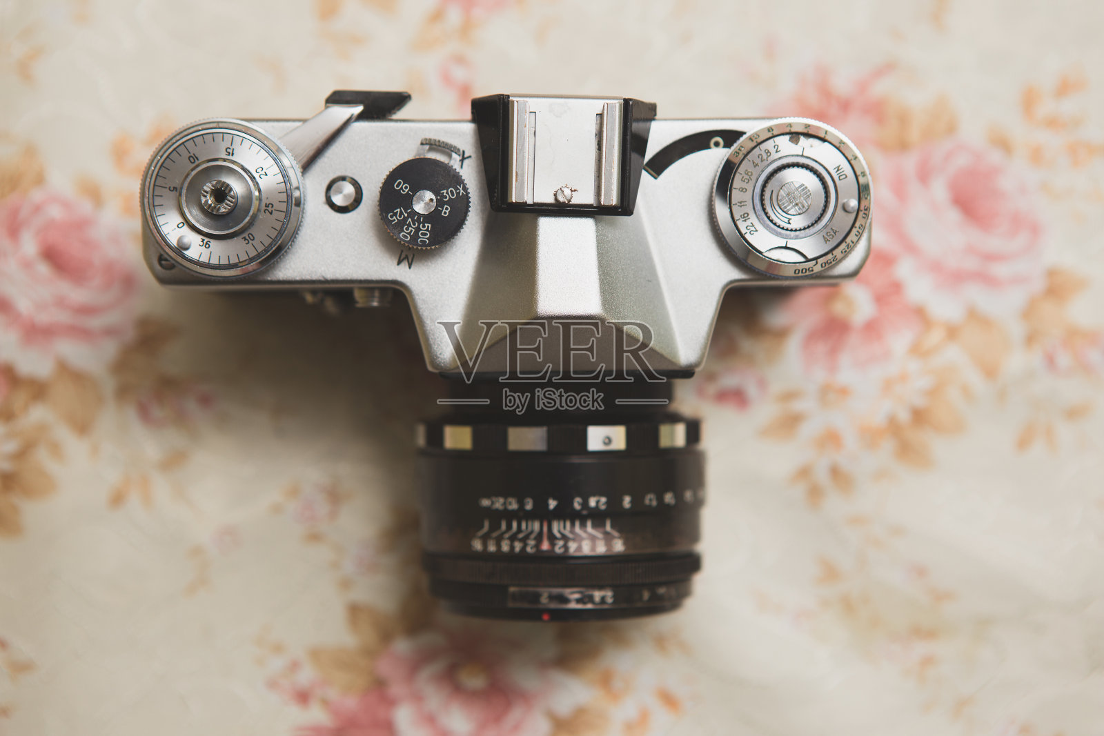 他低头看着一架老式模拟金属照相机。这台照相机很旧，坏了。在它下面是一块旧桌布。照片摄影图片