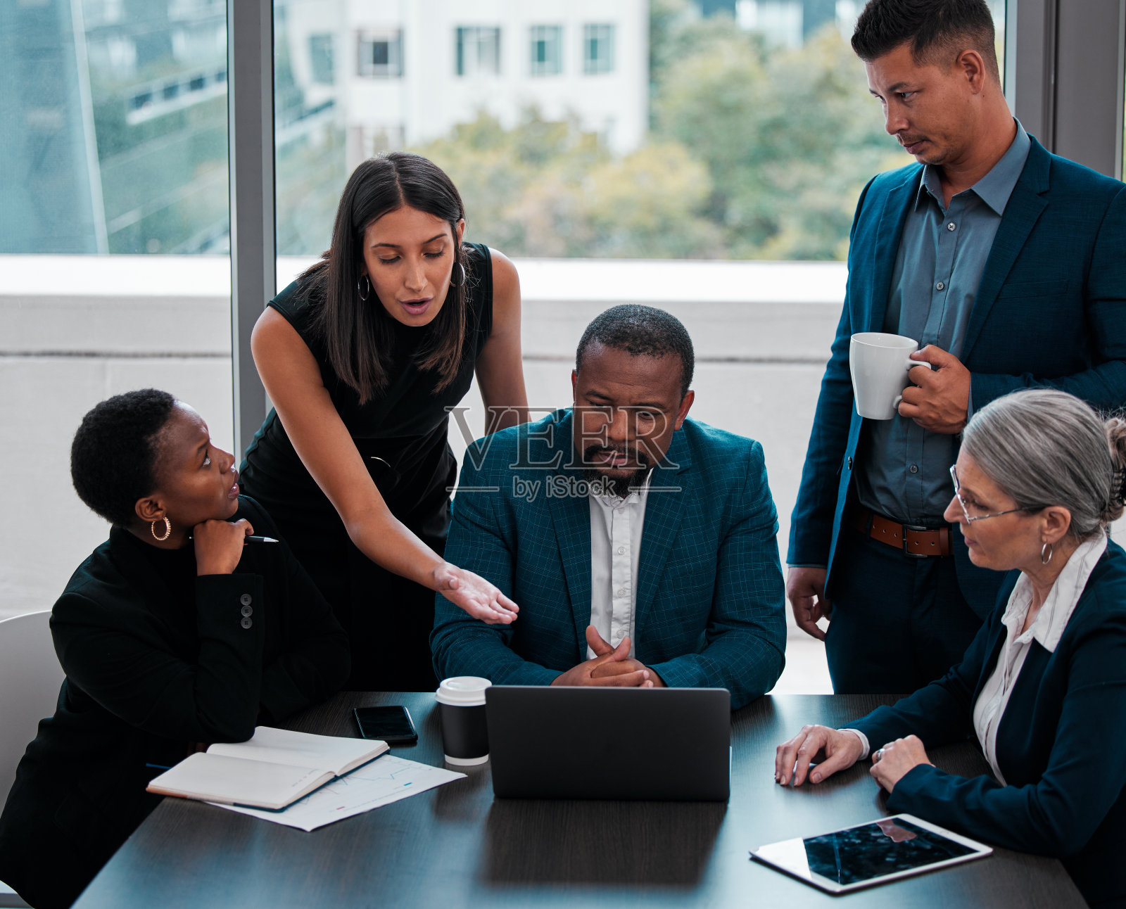 这是一群商务人士聚集在办公室的一台笔记本电脑旁的照片照片摄影图片