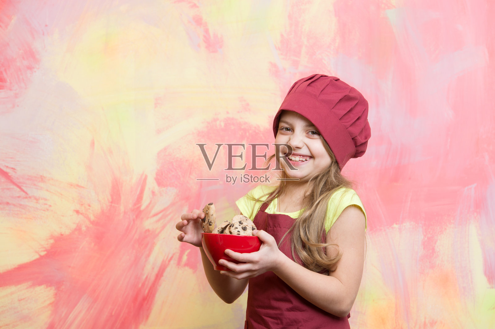 厨师小孩戴着厨师帽，围裙上拿着饼干照片摄影图片