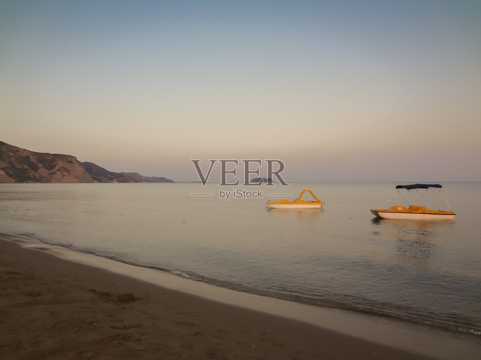 美丽的日出在海上与脚踏船在绿松石海滩在希腊照片摄影图片