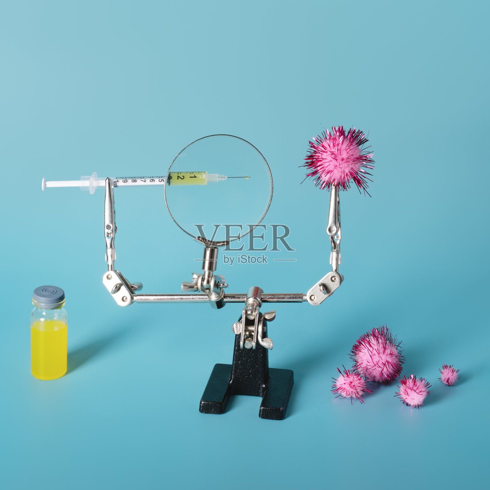 注射器，装有被放大镜放大的黄色液体，准备刺穿小瓶和病毒旁边的病毒粒子。医学和检疫的概念。副本的空间。照片摄影图片