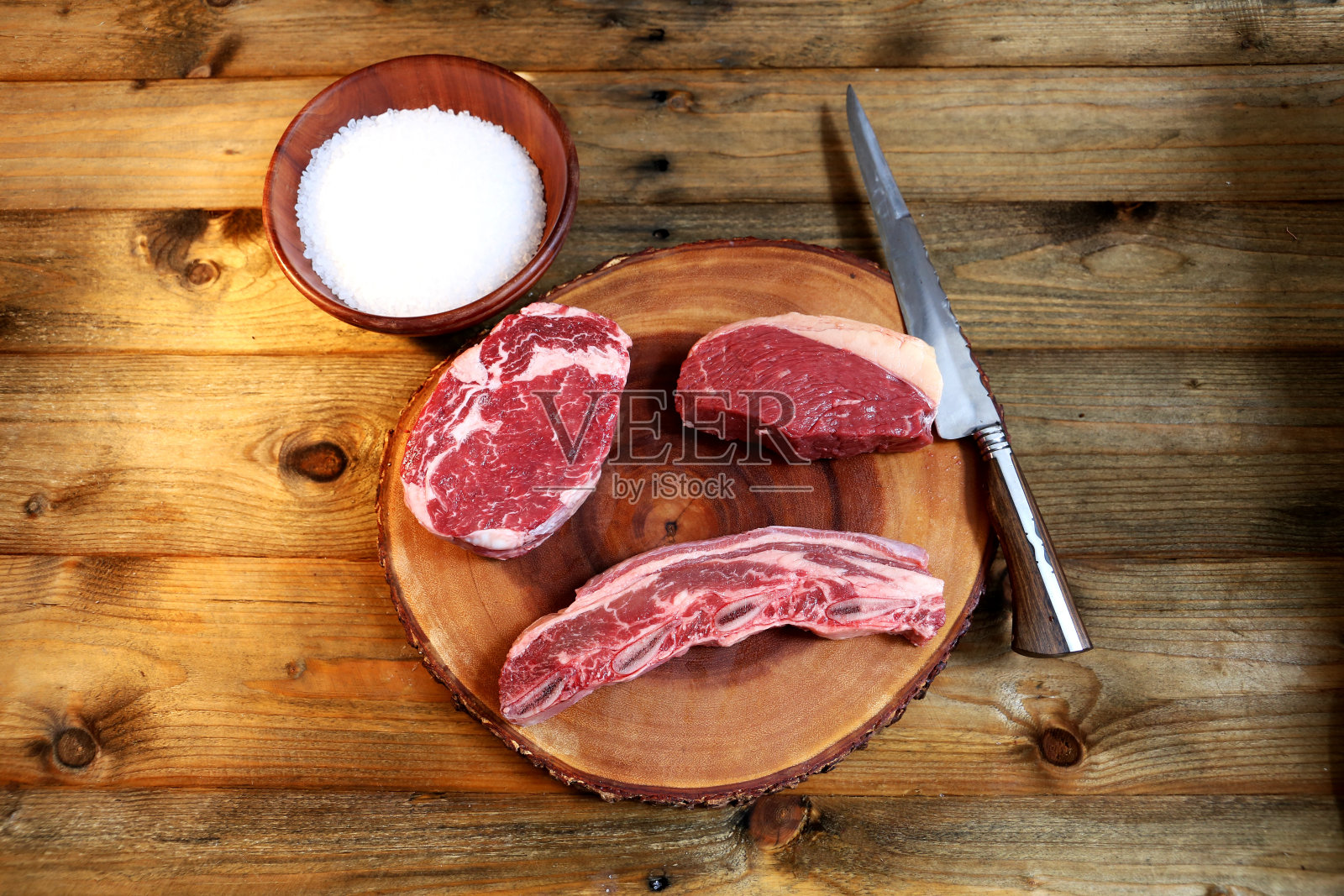 在木板下切特殊的肉，旁边放一把刀。乡村木背景照片摄影图片