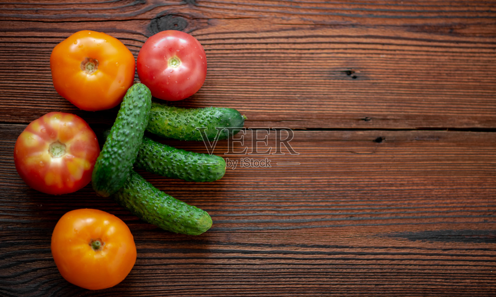 木背景上放着新鲜的黄瓜和西红柿。照片摄影图片