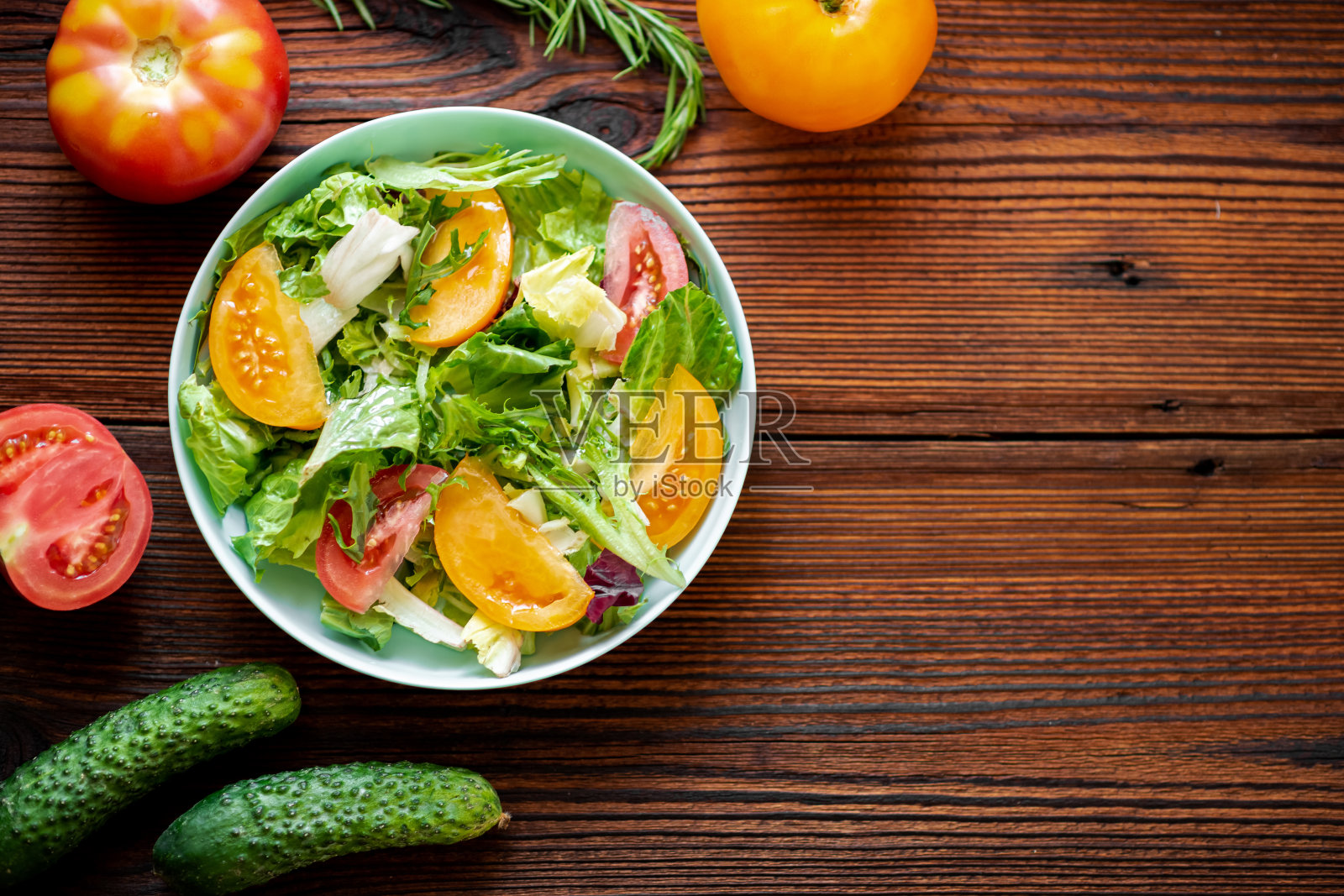 健康的沙拉新鲜的蔬菜，香草和西红柿在木制的背景。放置你的文本。照片摄影图片
