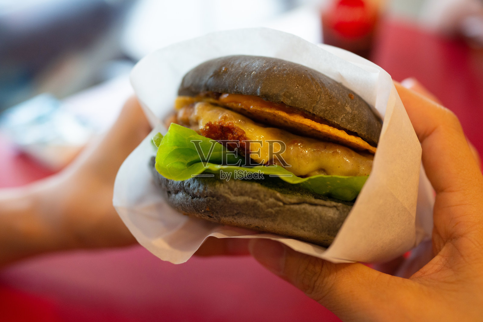 特写成年人的手拿着一个汉堡，准备吃。照片摄影图片