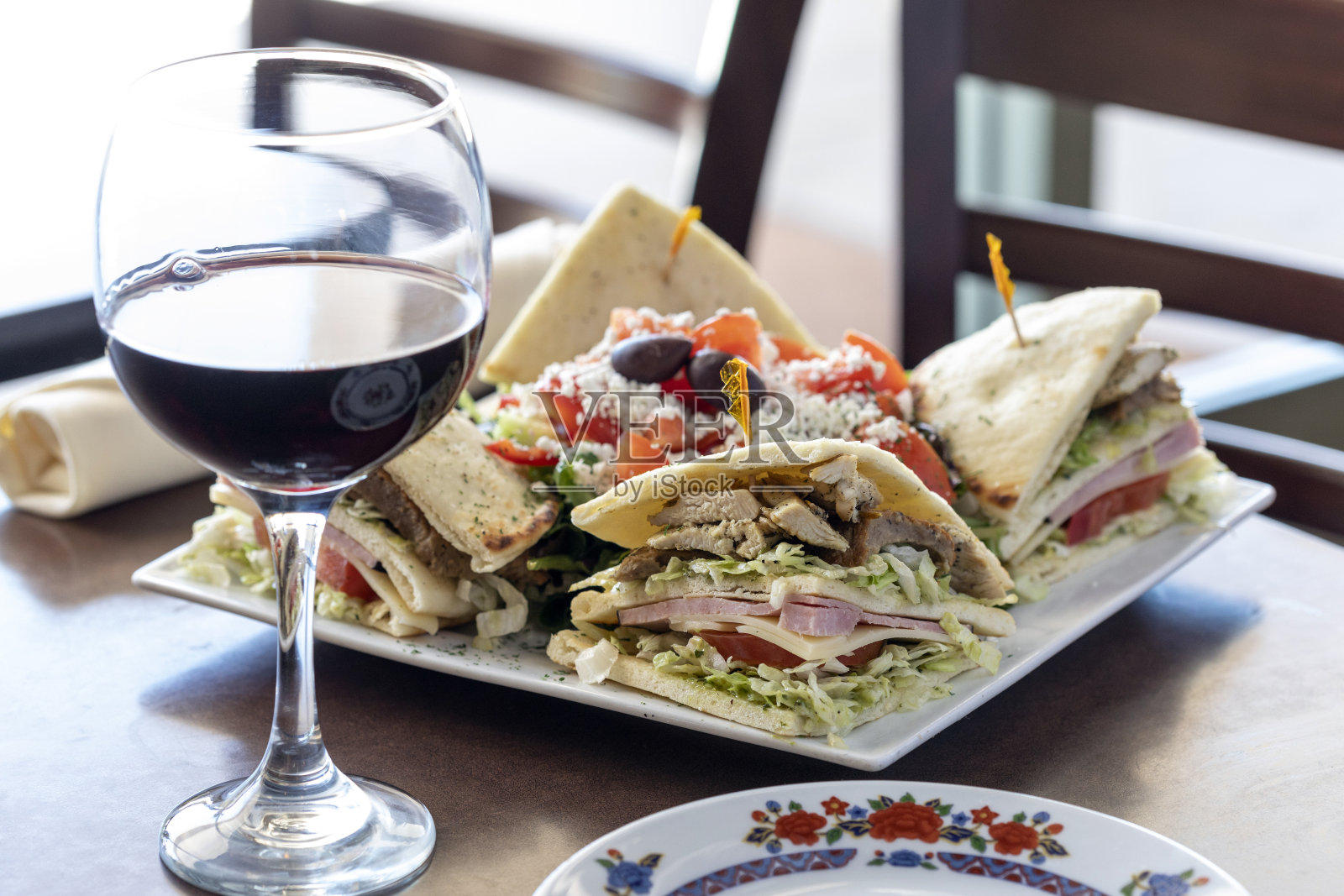 地中海式三明治装饰盘和桌上的一杯葡萄酒照片摄影图片