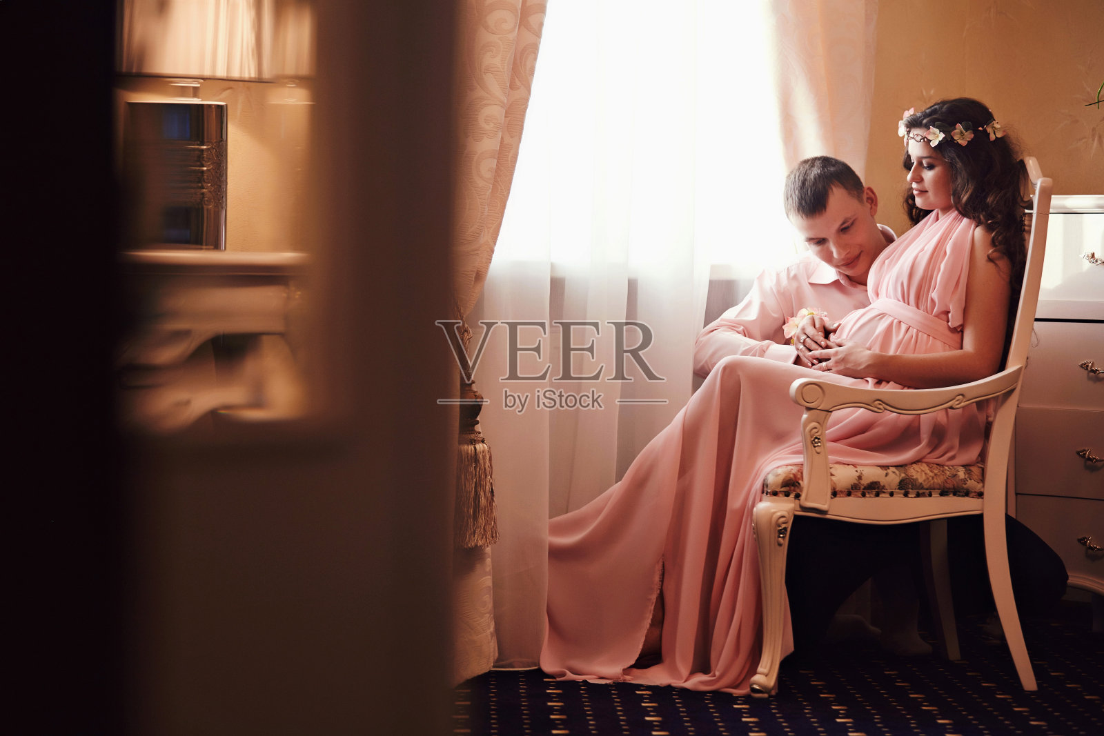 一名孕妇和一名男子在窗边摆着古典室内造型。等待一个孩子。怀孕照片摄影图片