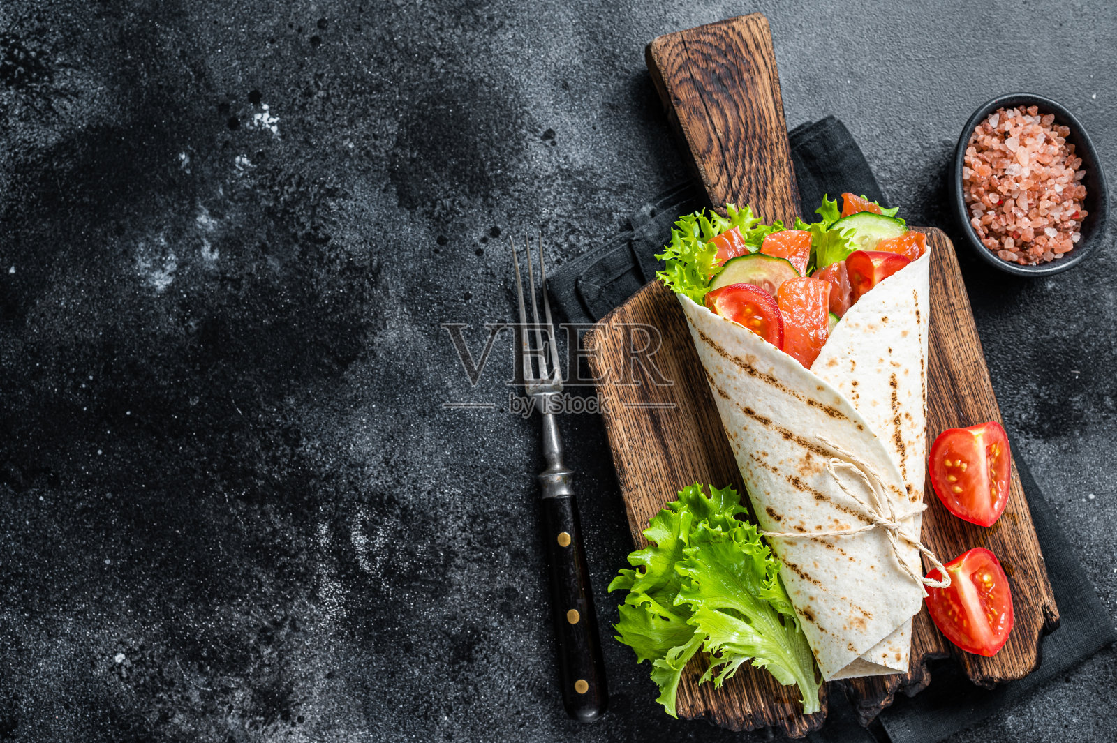 把三文鱼卷和沙拉，蔬菜一起卷起来。黑色背景。前视图。本空间照片摄影图片