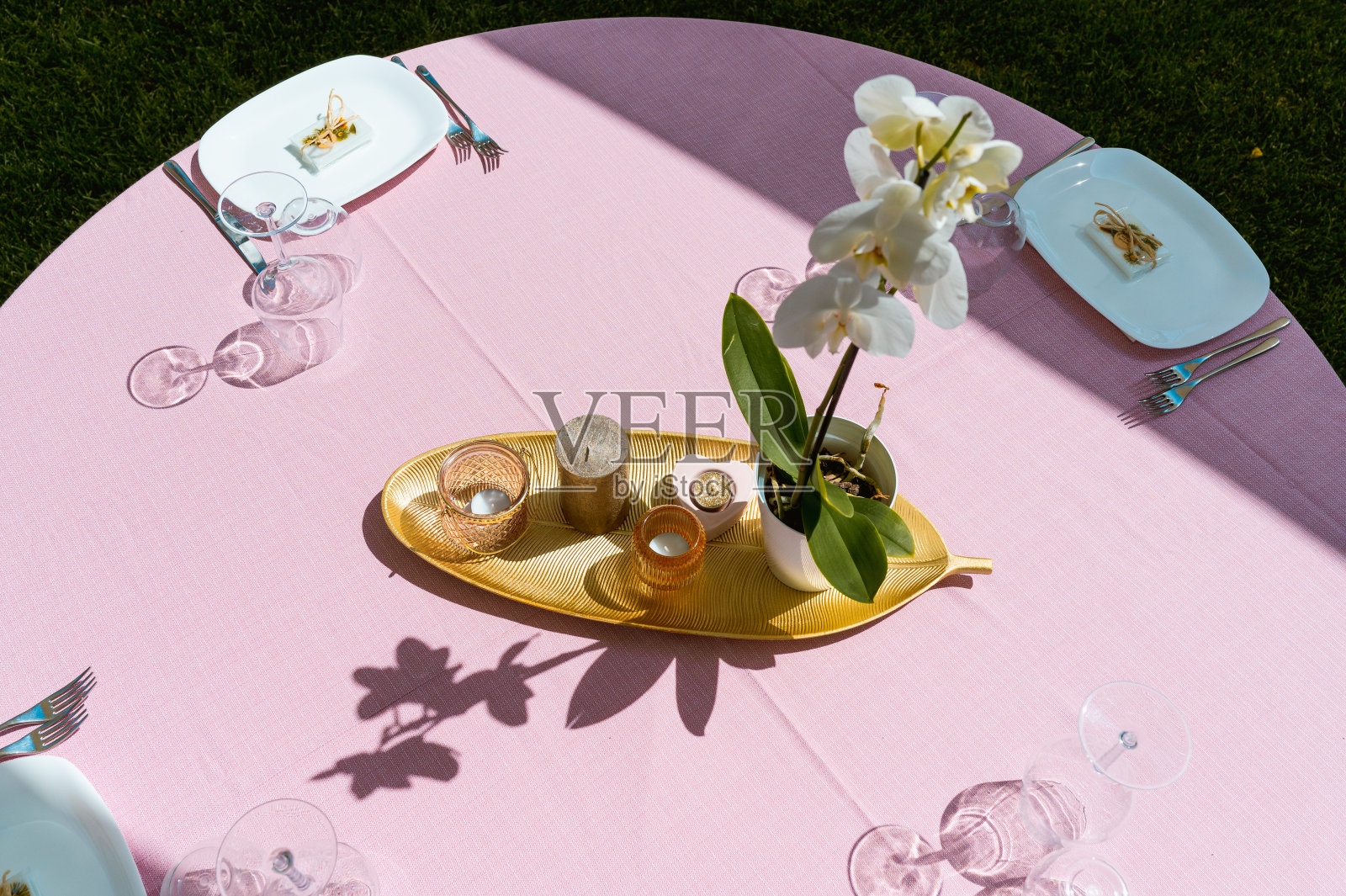 餐桌上优雅的中心装饰品，点缀着蜡烛、金色的细节和兰花花。照片摄影图片
