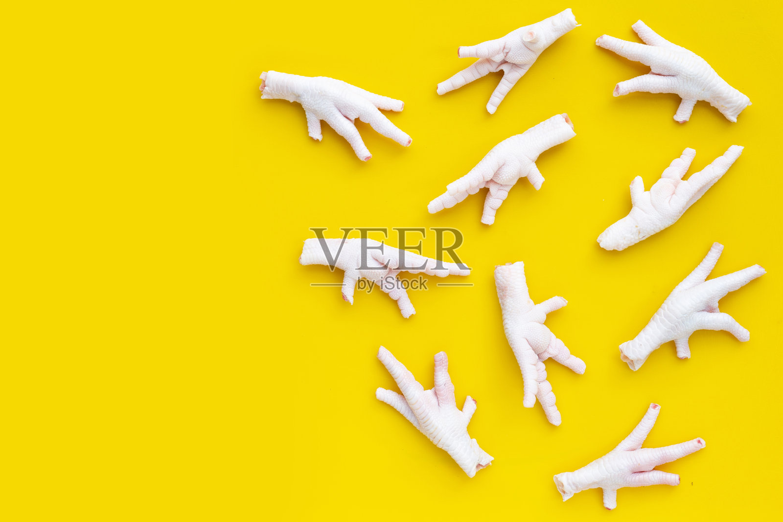 黄色背景上的生鸡爪。照片摄影图片