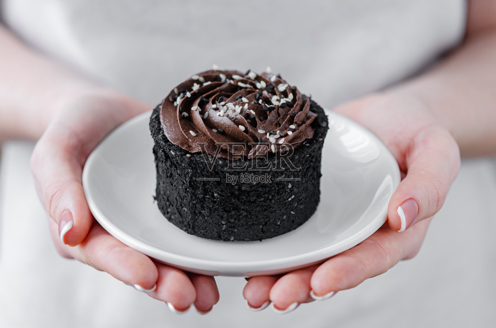 女人手里拿着一盘巧克力蛋糕。照片摄影图片