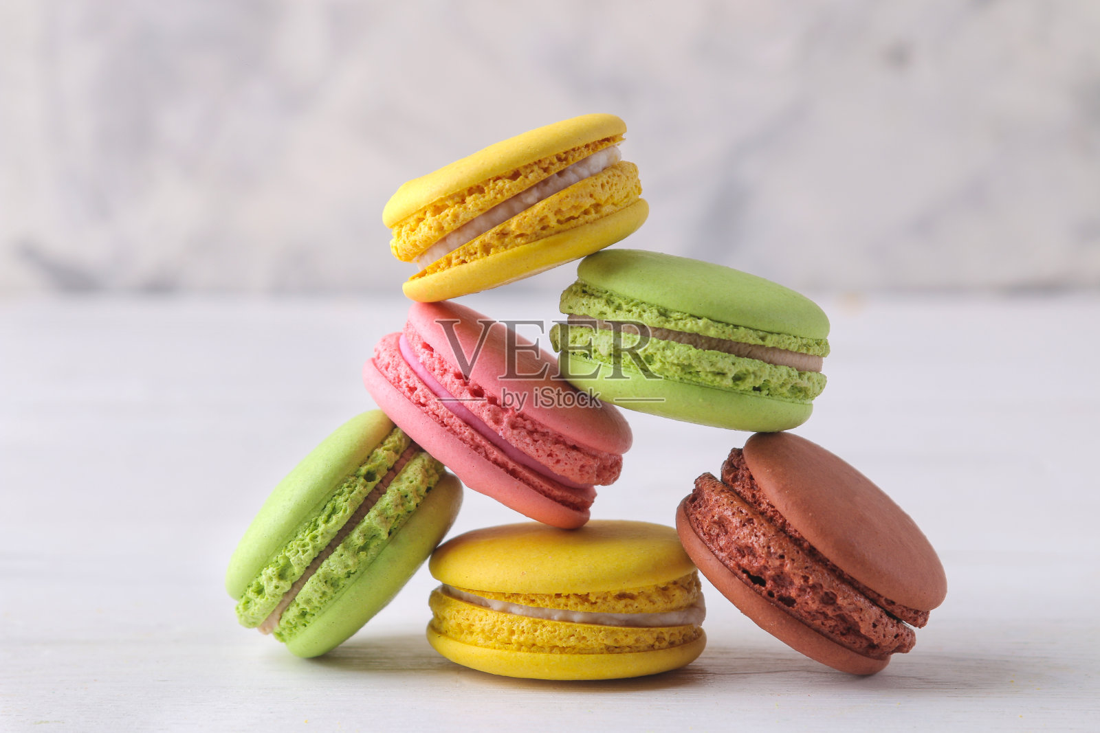 蛋白杏仁饼干。白色木桌上放着美味的彩色法国通心粉蛋糕。照片摄影图片