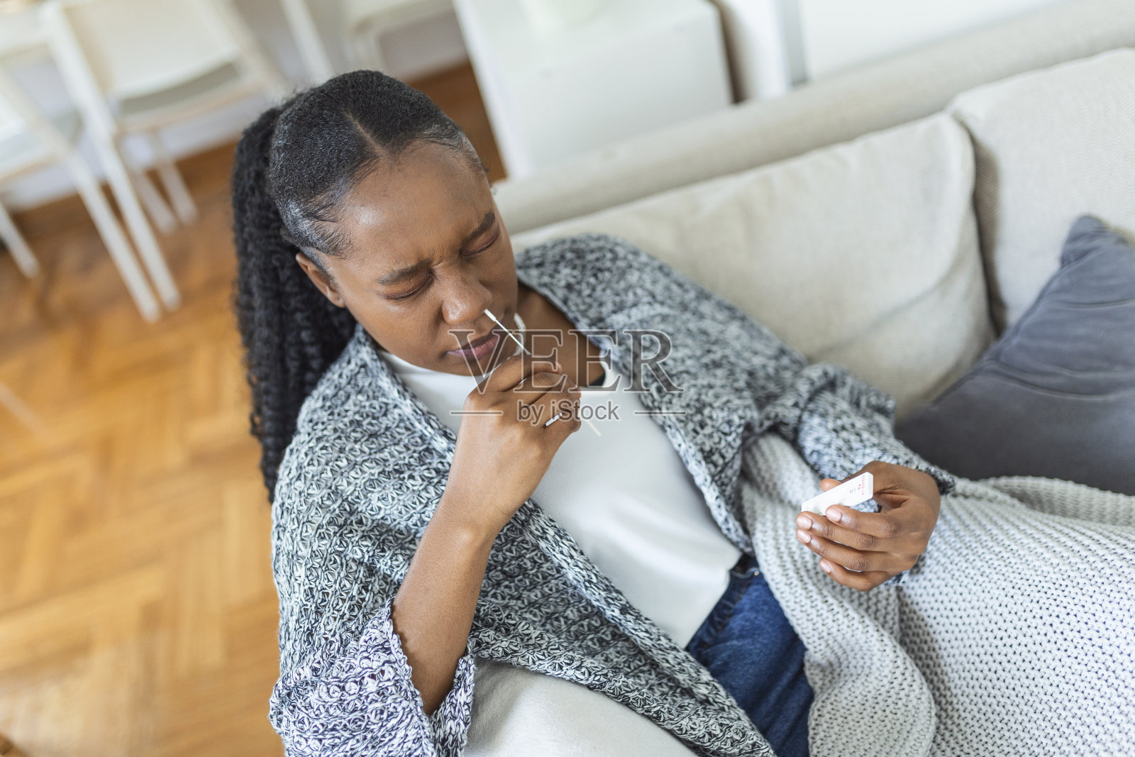 非裔美国妇女在家里做冠状病毒PCR检测时使用棉签。使用冠状病毒快速诊断测试的妇女。年轻女性在家中使用鼻拭子检测COVID-19。照片摄影图片