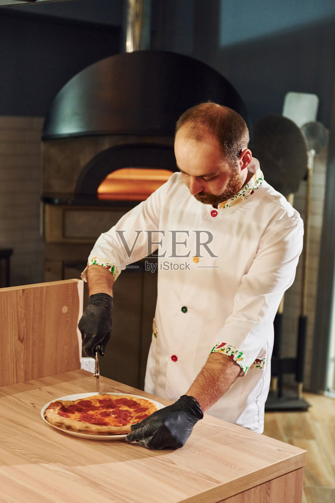 穿着白衣服的厨师在餐厅厨房里准备美味的披萨照片摄影图片