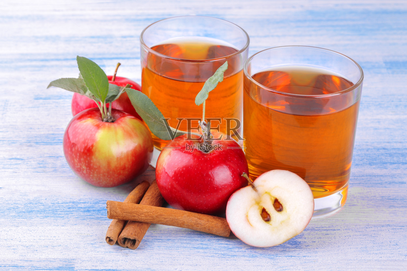 苹果汁，新鲜成熟的苹果和肉桂棒在蓝色的木头背景照片摄影图片