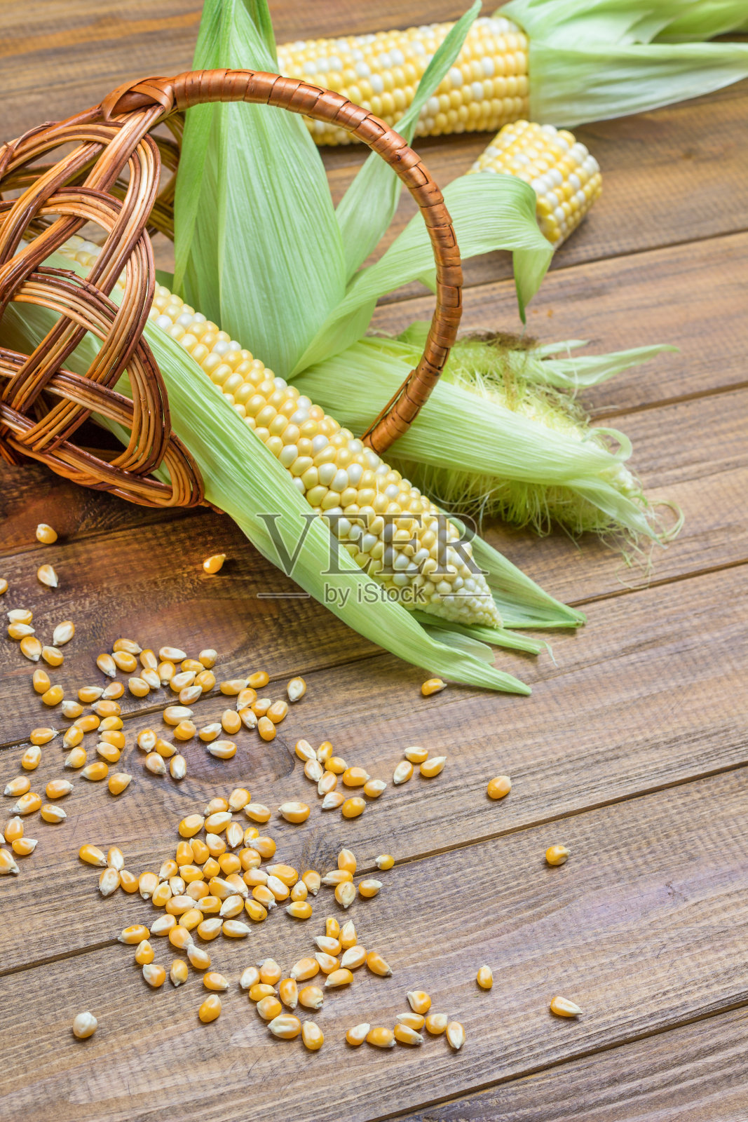 桌上的谷物。柳条篮子里的生玉米芯。照片摄影图片