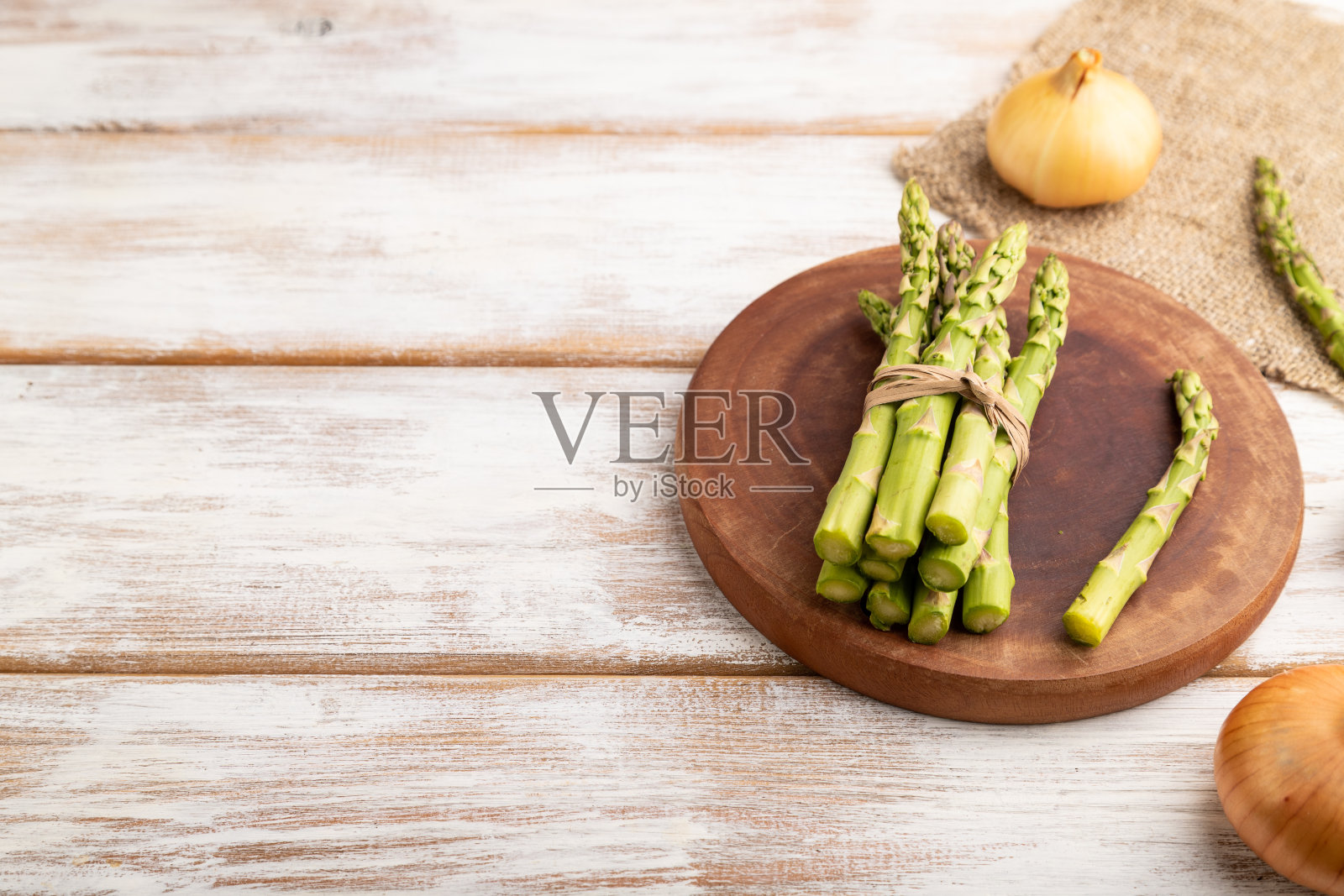 一束新鲜的绿芦笋，大蒜，洋葱在白色的木质背景上。侧视图，拷贝空间。收获，健康，素食，概念。照片摄影图片