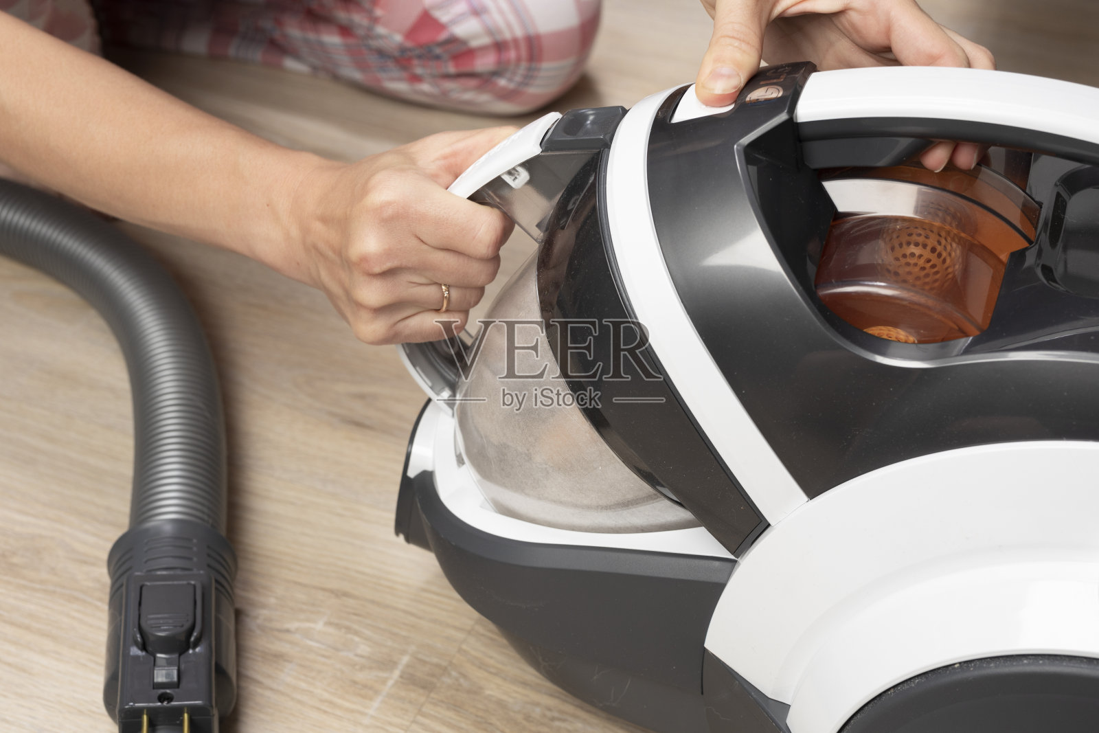 一名妇女从真空吸尘器中取出一个容器。家务、打扫卫生照片摄影图片